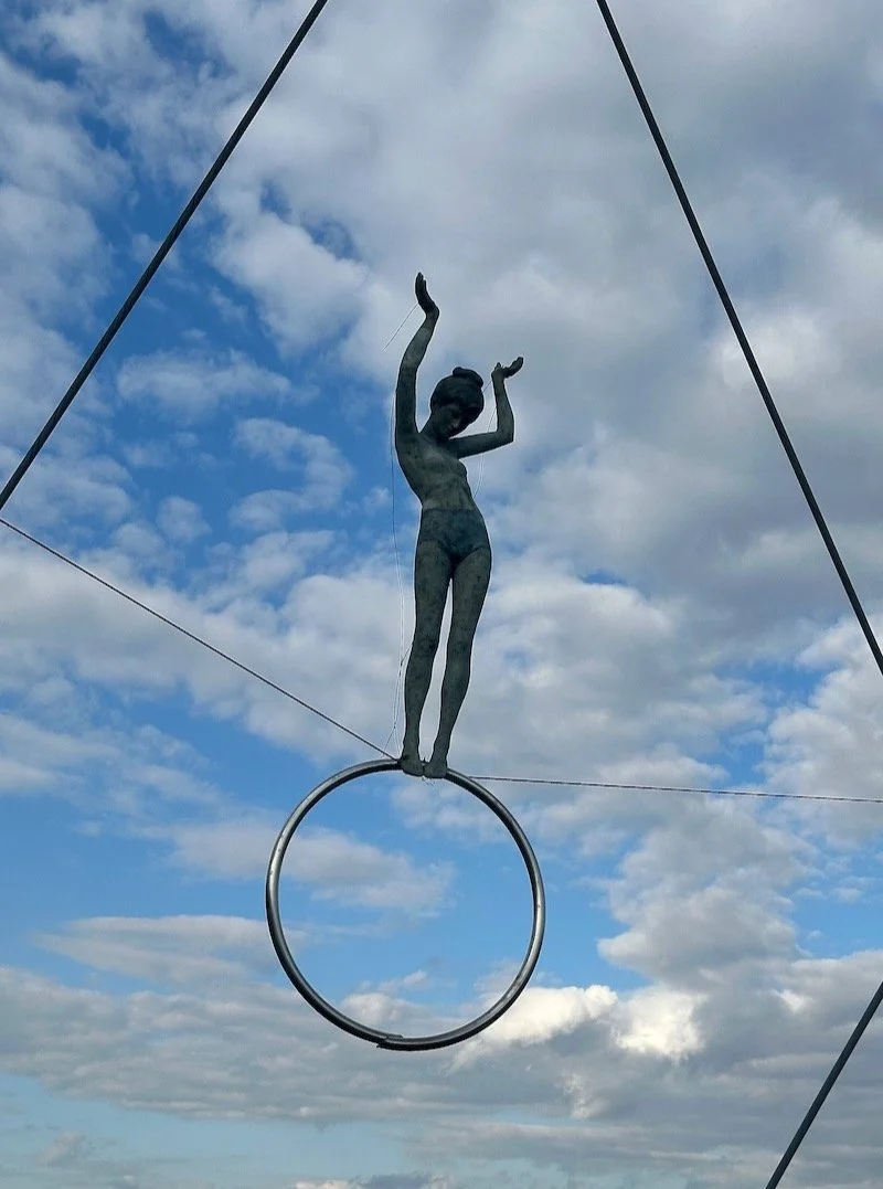 Travel Tips Tuesday inspiration from the historic Kazimeierz district of Krakrów, Poland, where, just outside the intimate neighborhood, sculptures of acrobats hang from wires on the Vistula River’s Father Bernatek Bridge in a seemingly