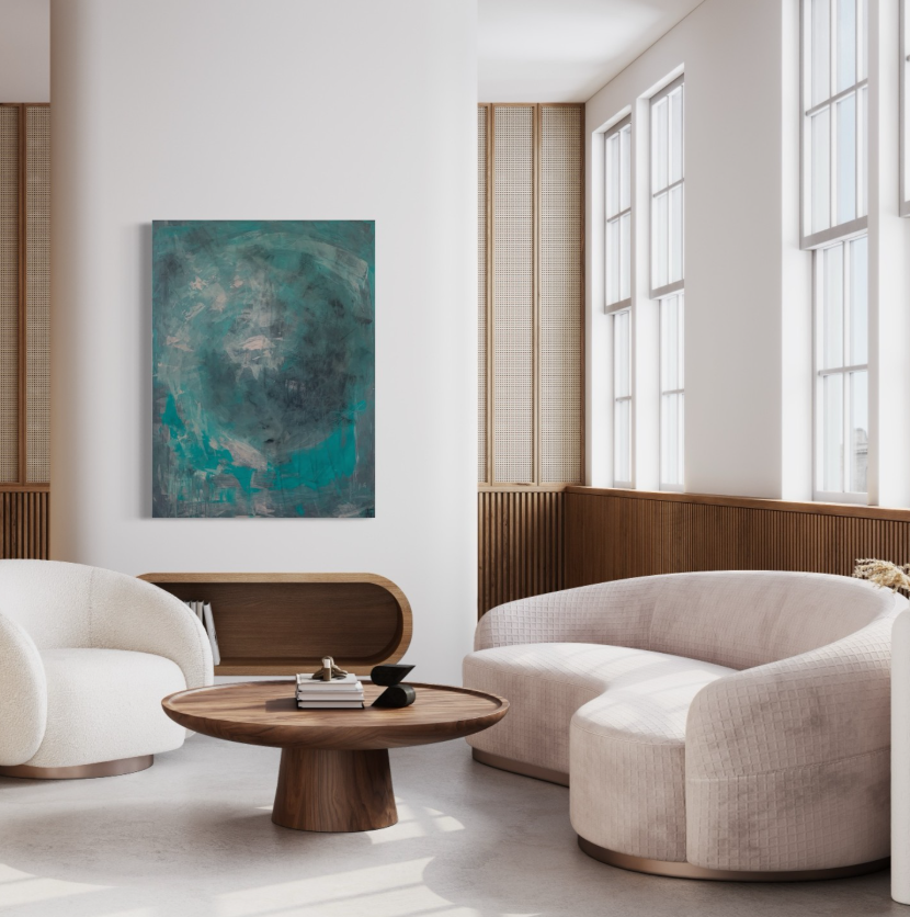 Modern living room with light-colored curved sofa, round wooden coffee table with books and decor, abstract teal and blue painting on wall, large windows letting in natural light, wood-paneled wall accents.