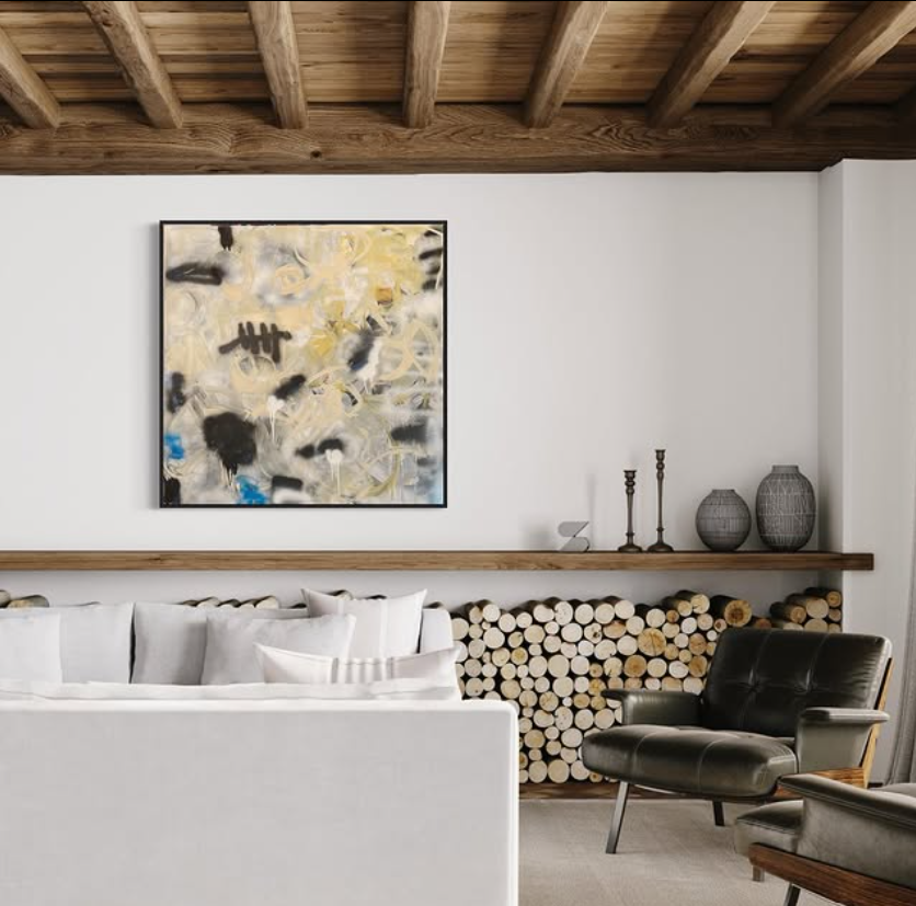 Living room with white sofa, black leather armchair, wooden ceiling, abstract painting, and logs stacked against the wall.