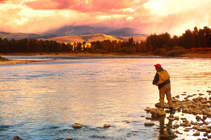 a man fly fishing in Montana at sunset