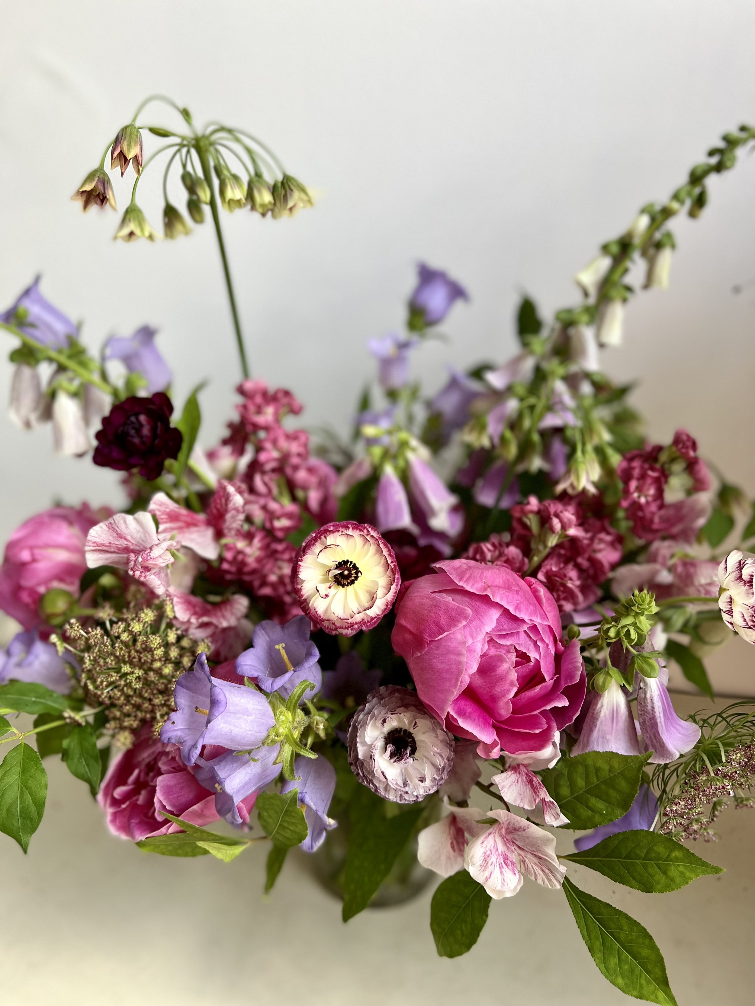 pink and purple spring floral arrangement with peonies, ranunculus and foxglove
