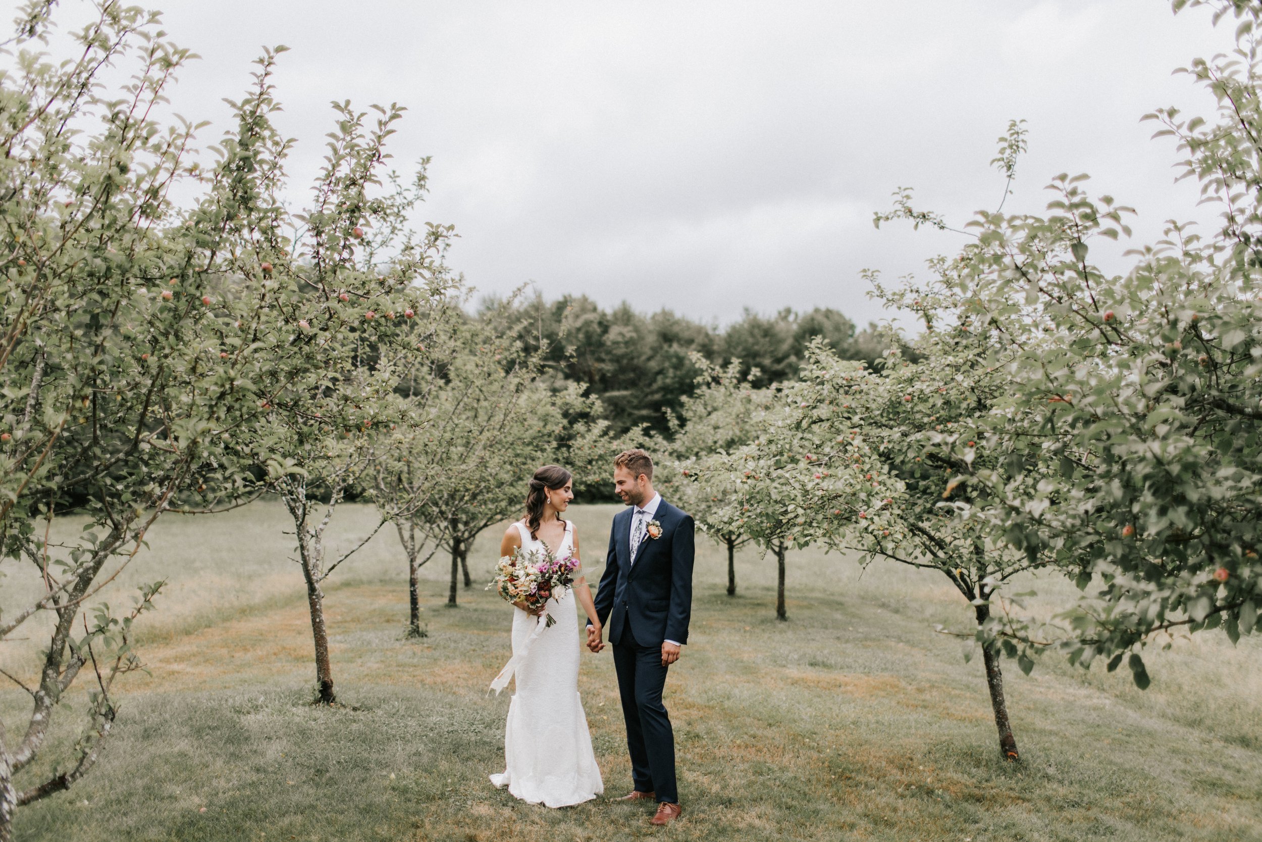 Bride and Groom Stand in Maine Orchard 