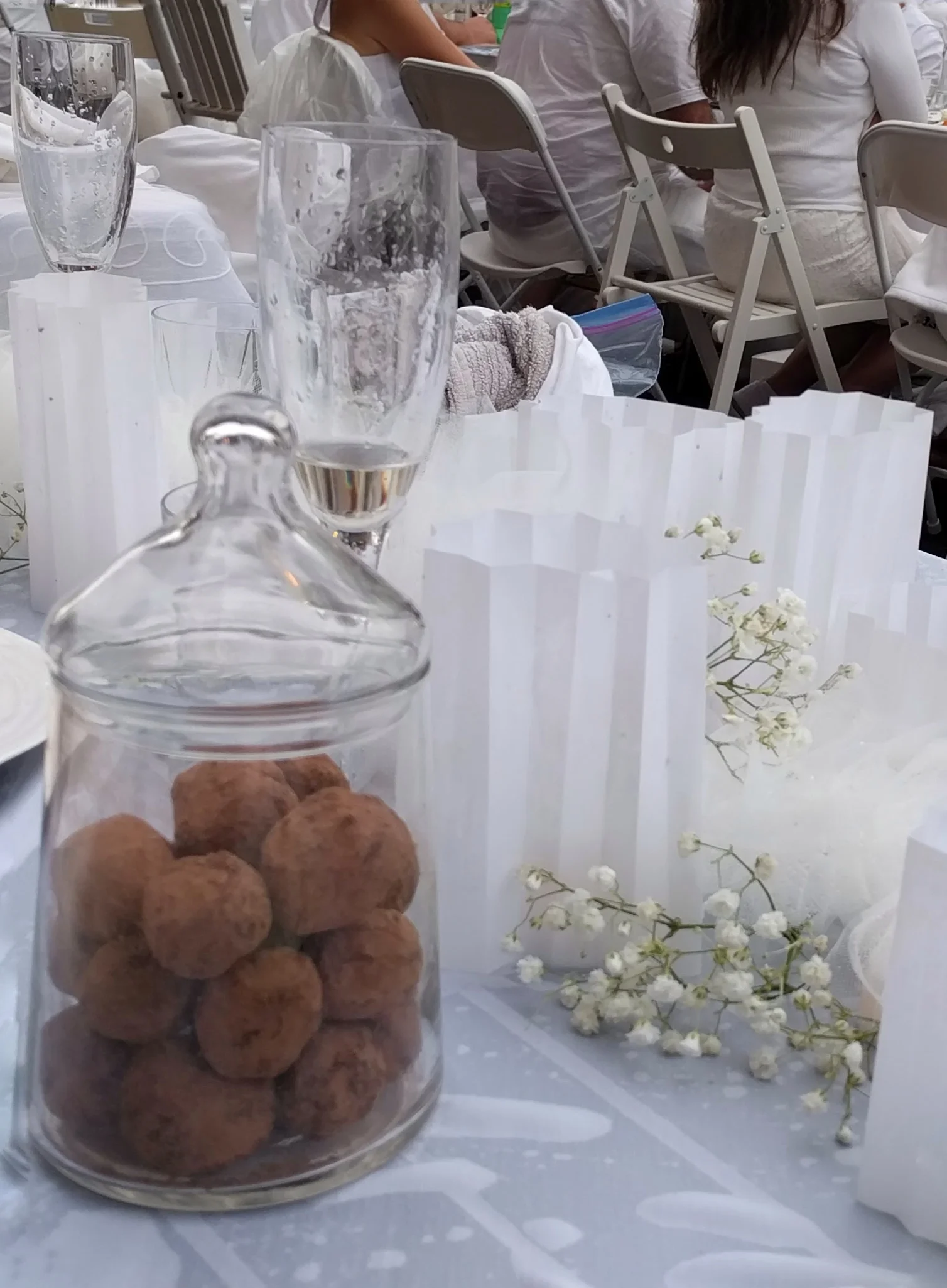 Decorating the table with food and flowers (without greenery - just sprigs of baby's breath tucked among tulle pompoms and vellum shades over candles. 