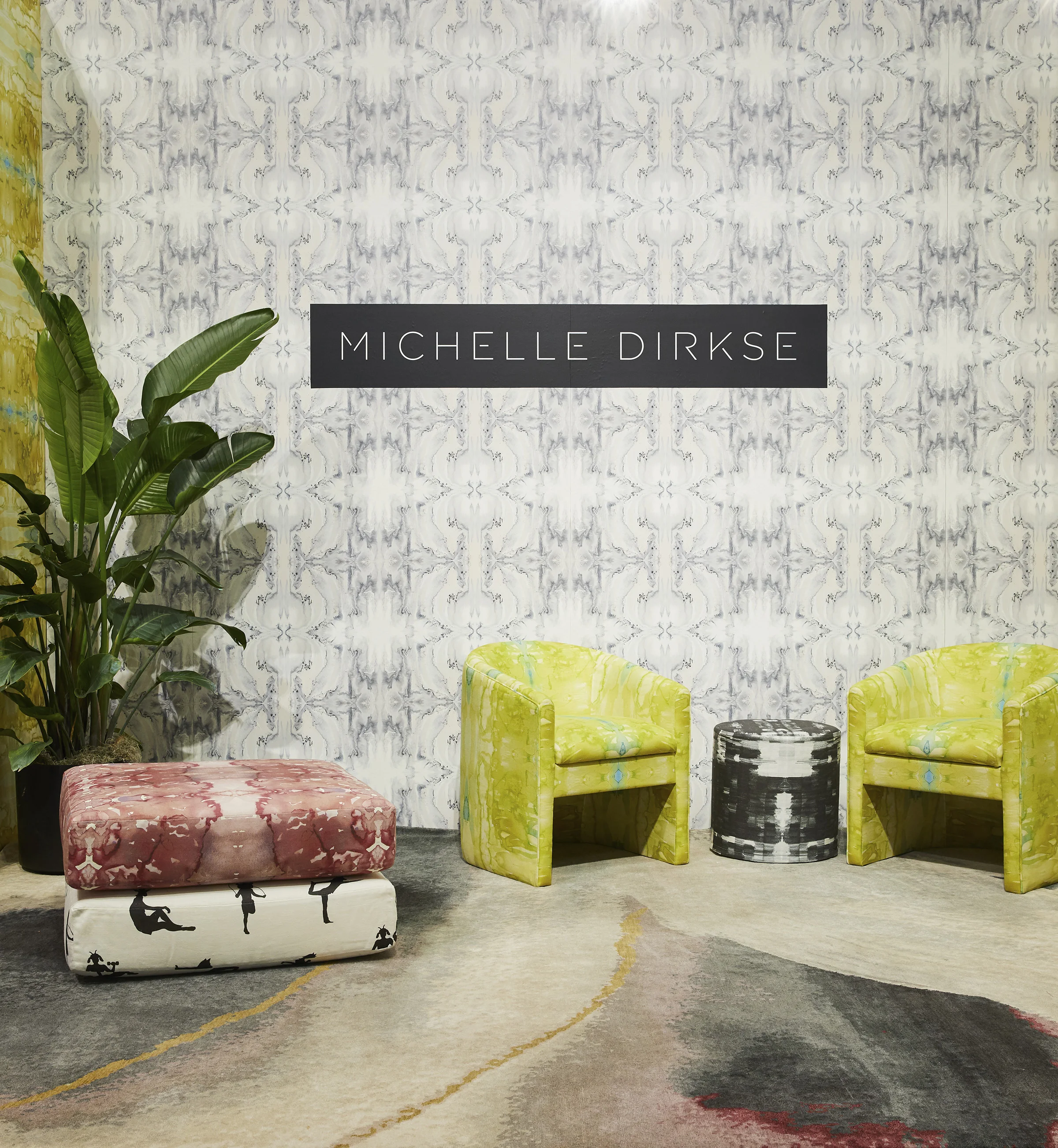 image of repeating Essence wallpaper with two chairs upholstered in yellow Cenote fabric and round ottoman in Sketches fabric, and cushions in Animal Gym and Seaweed fabric with a banana plant and patterned rug for interior designers