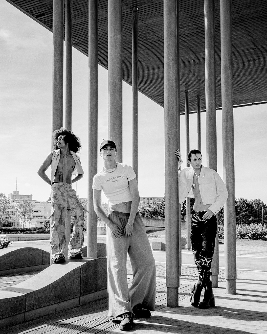 Stunning black-and-white photo of three models posing confidently under modern pillars, captured by a prestigious London fashion photographer. This global style visionary excels in editorial photography and commercial projects, offering dynamic shots