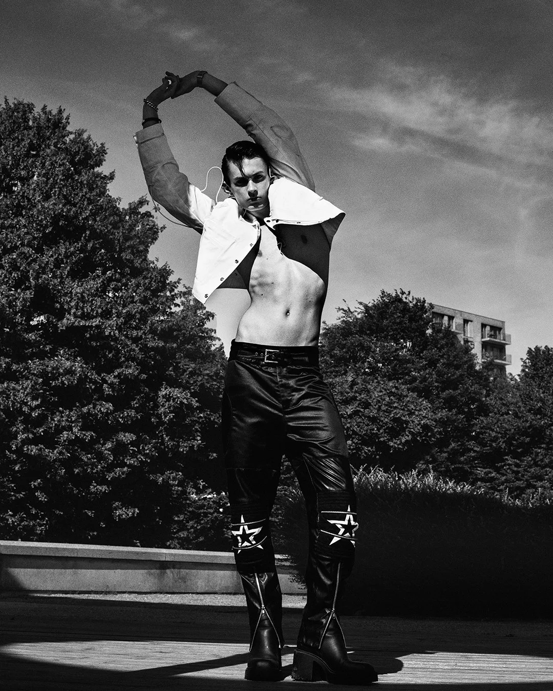 Dramatic monochrome shot featuring a model in an open jacket, leather pants with star accents, and high boots, photographed by a leading international fashion photographer from London. Ideal for commercial shoots and fashion magazine spreads, this im