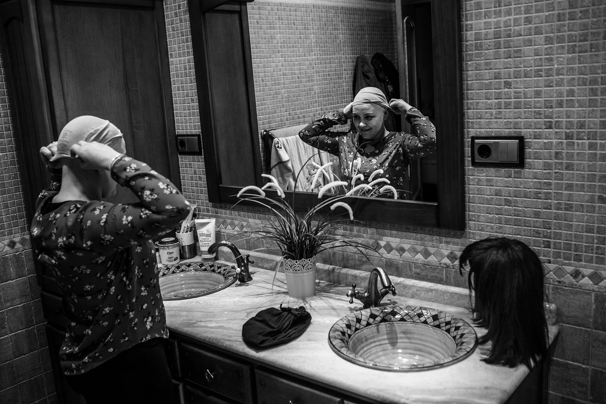 Raquel, sometida actualmente a un tratamiento de quimioterapia, se pone la peluca en la casa de su pueblo, a unos 10 km de Murcia, España, diciembre 2017. (Manu Brabo/MeMo) 
