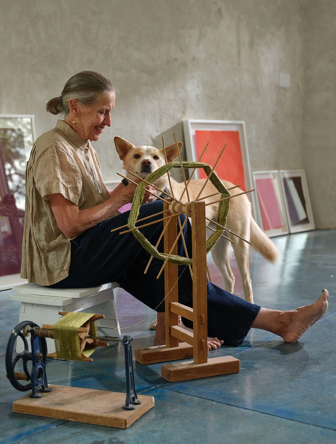 Polly Barton in her studio with a dog and artworks.