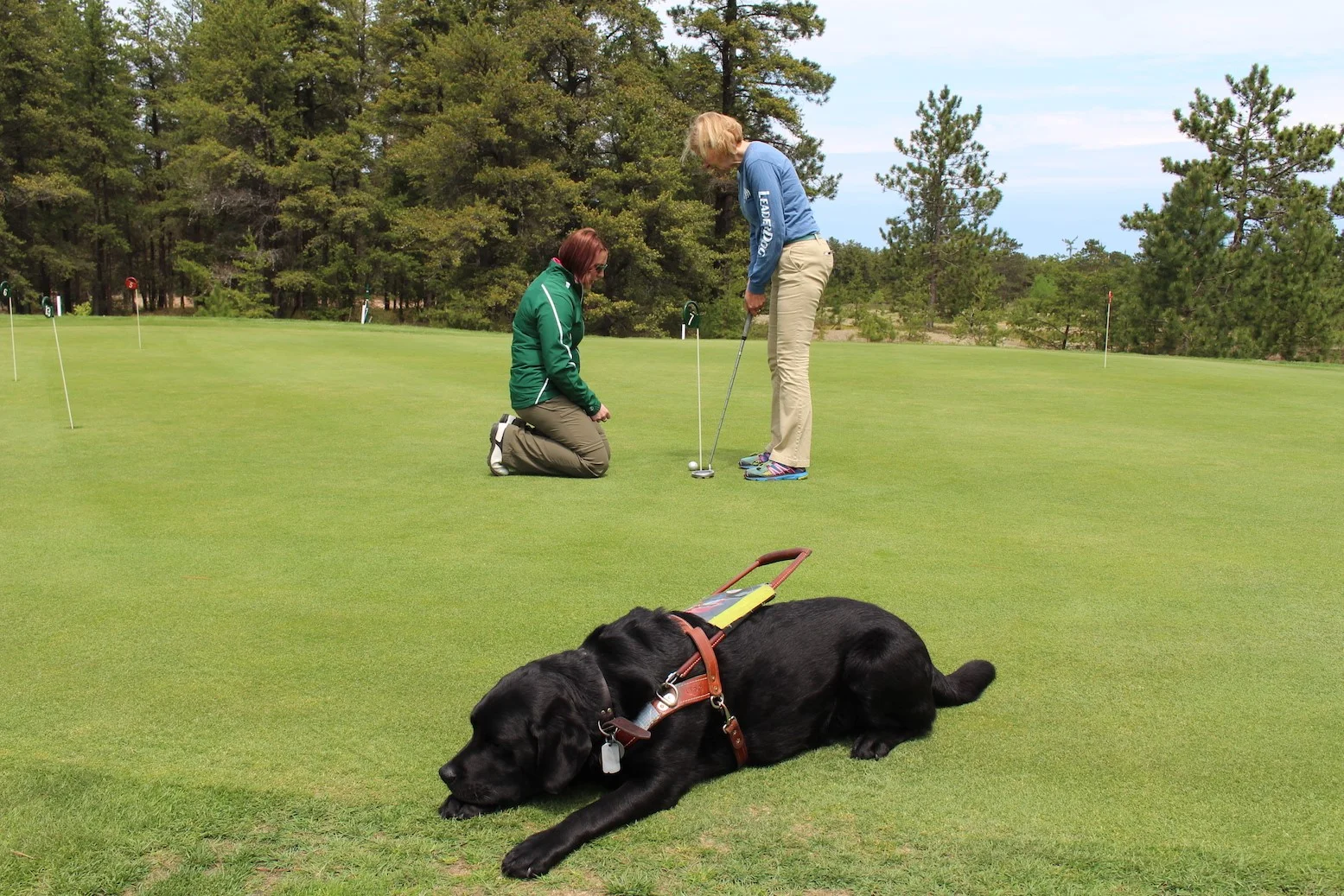 Preston golfing while her Leader dog Floyd enjoys a rest.