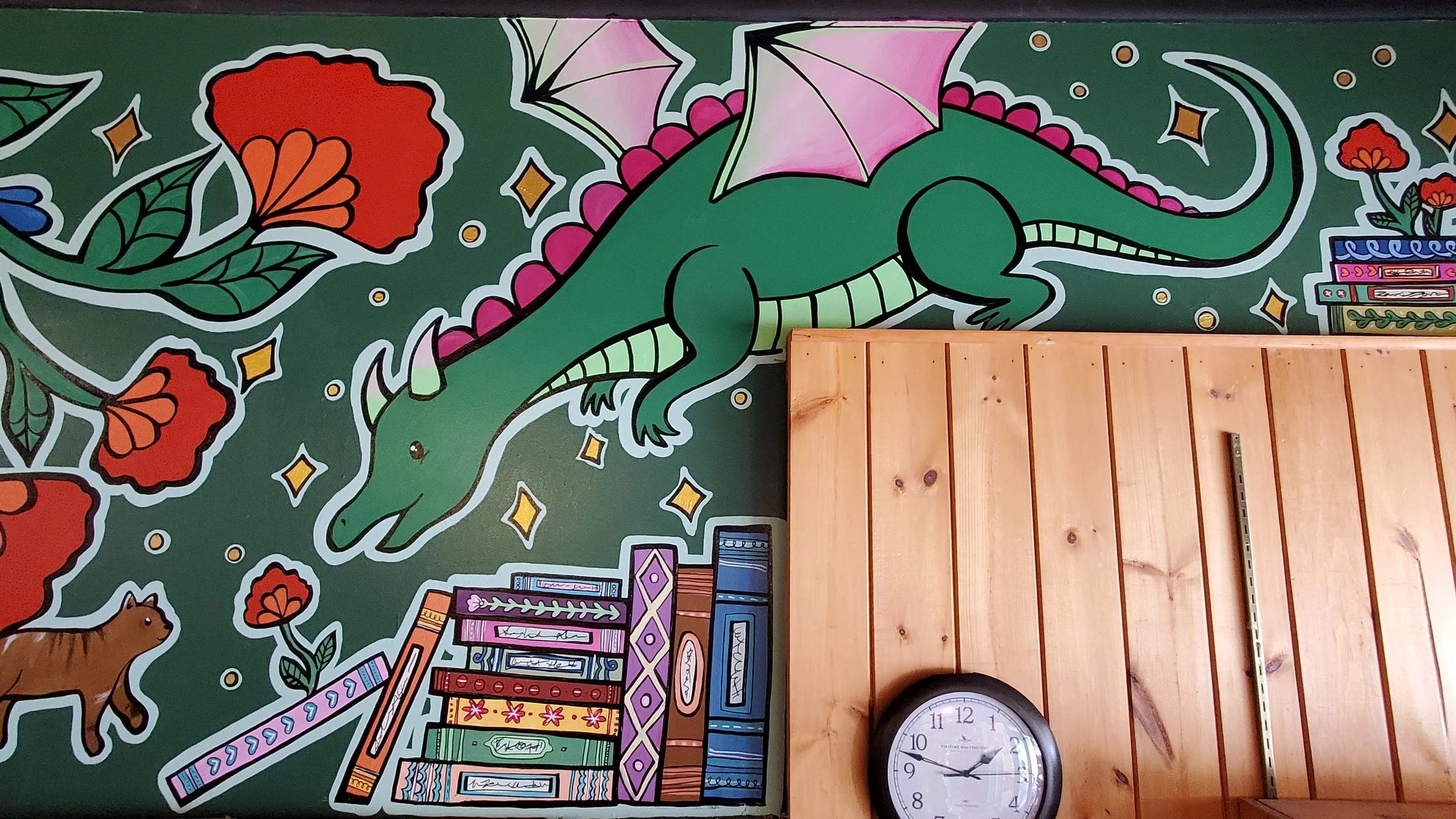 A last detail from the mural, from above the checkout desk, depicting a friendly green dragon with a hoard of books below and behind it