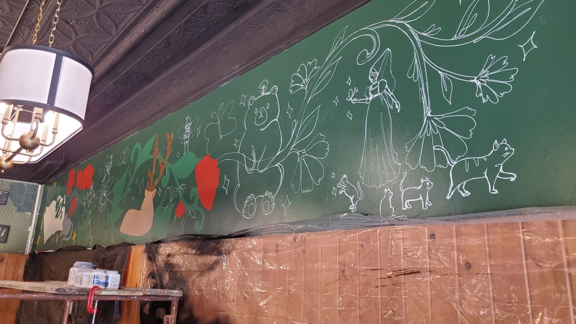A half-finished mural on the upper half of an interior wall in the bookstore