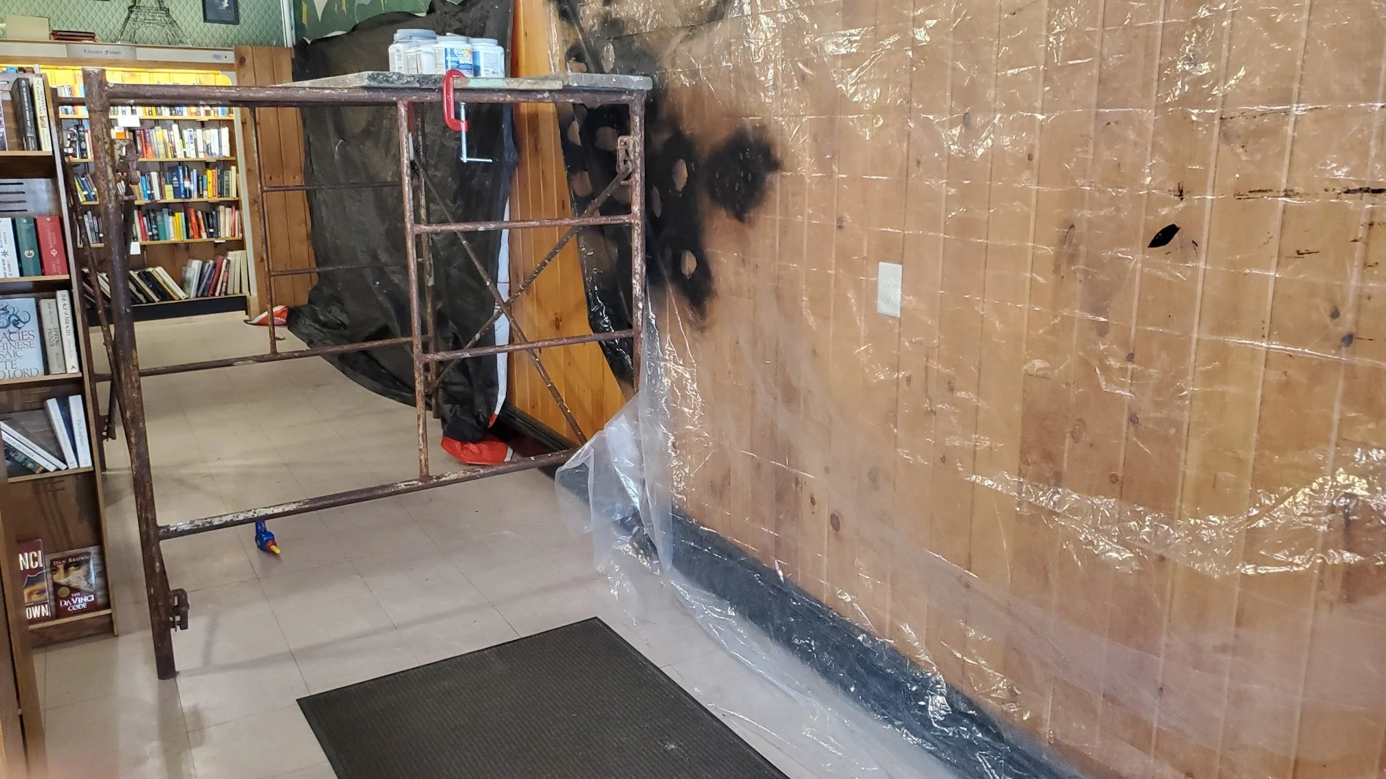 An interior photo of the bookstore, with plastic drop cloths protecting the walls, with scaffolding set up next to the walls