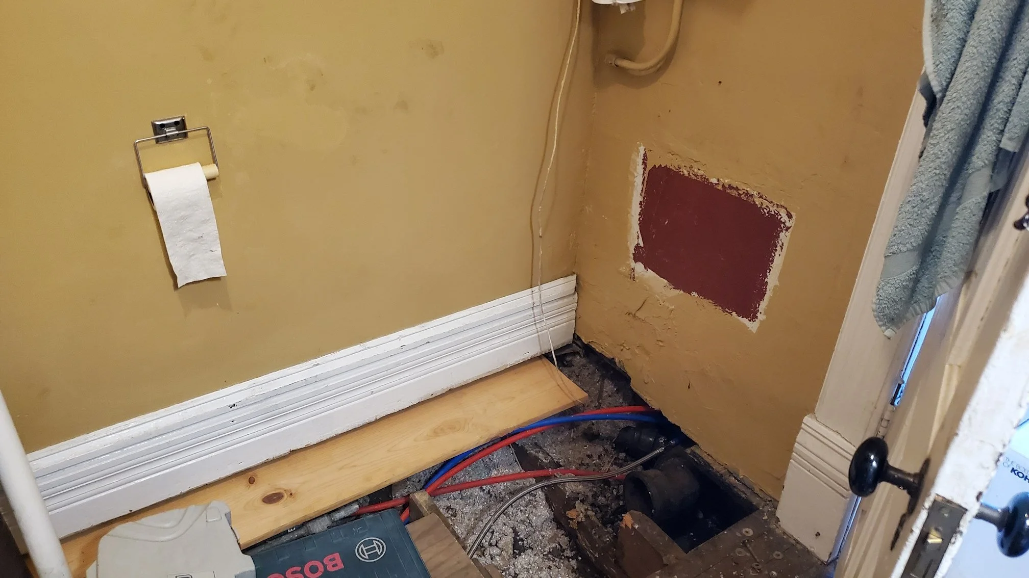 A photo of a torn-up bathroom, with a hole in the floor where a toilet should be