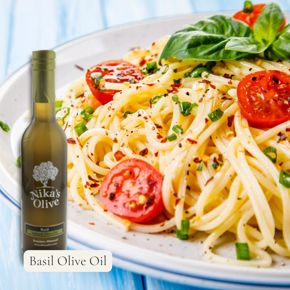 Bottle of basil olive oil next to a plate of pasta