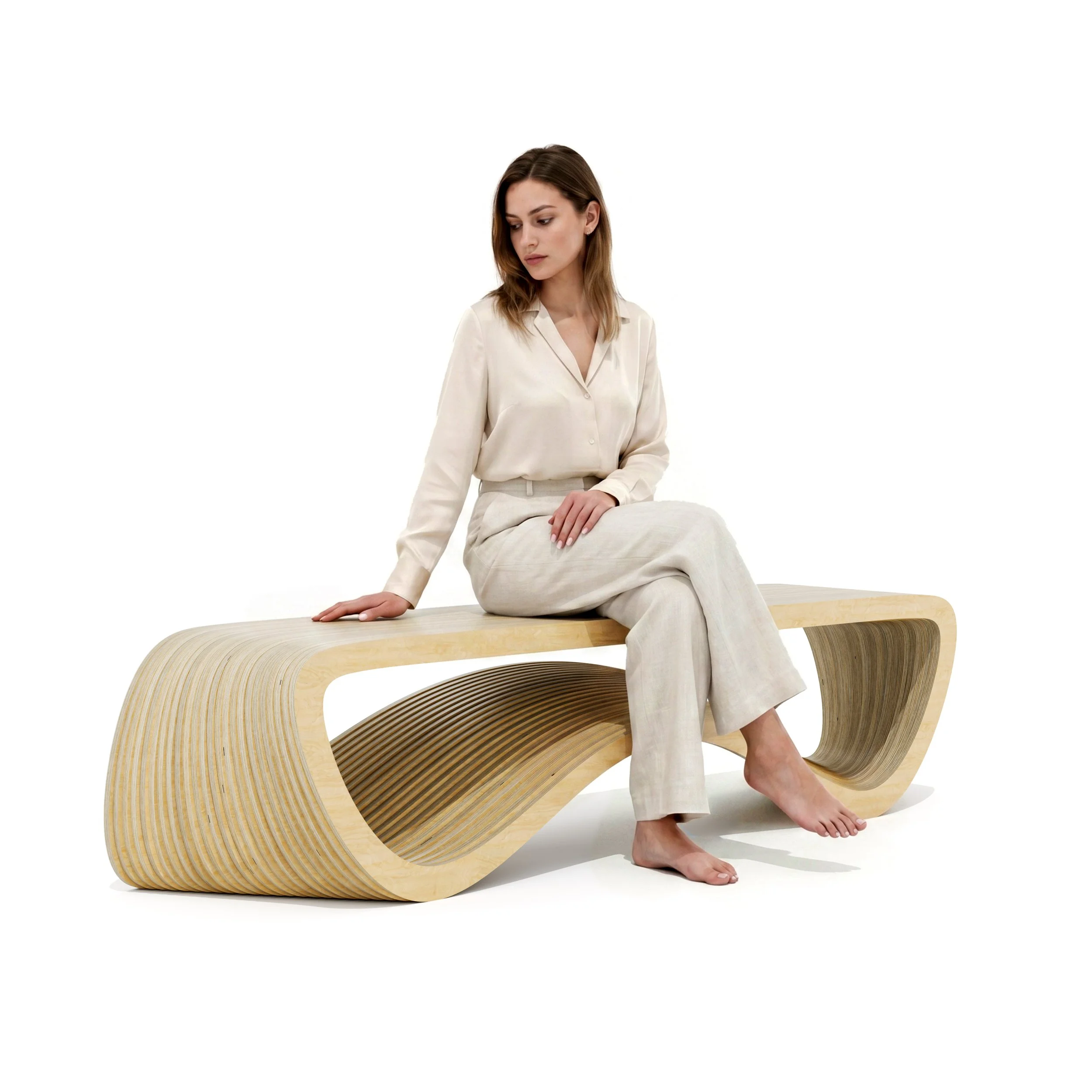 A woman dressed in beige pants and a cream blouse sitting on a modern, abstract wooden bench with a swooping and parametric design, with her right hand resting on the bench and her left hand on her lap, looking down.