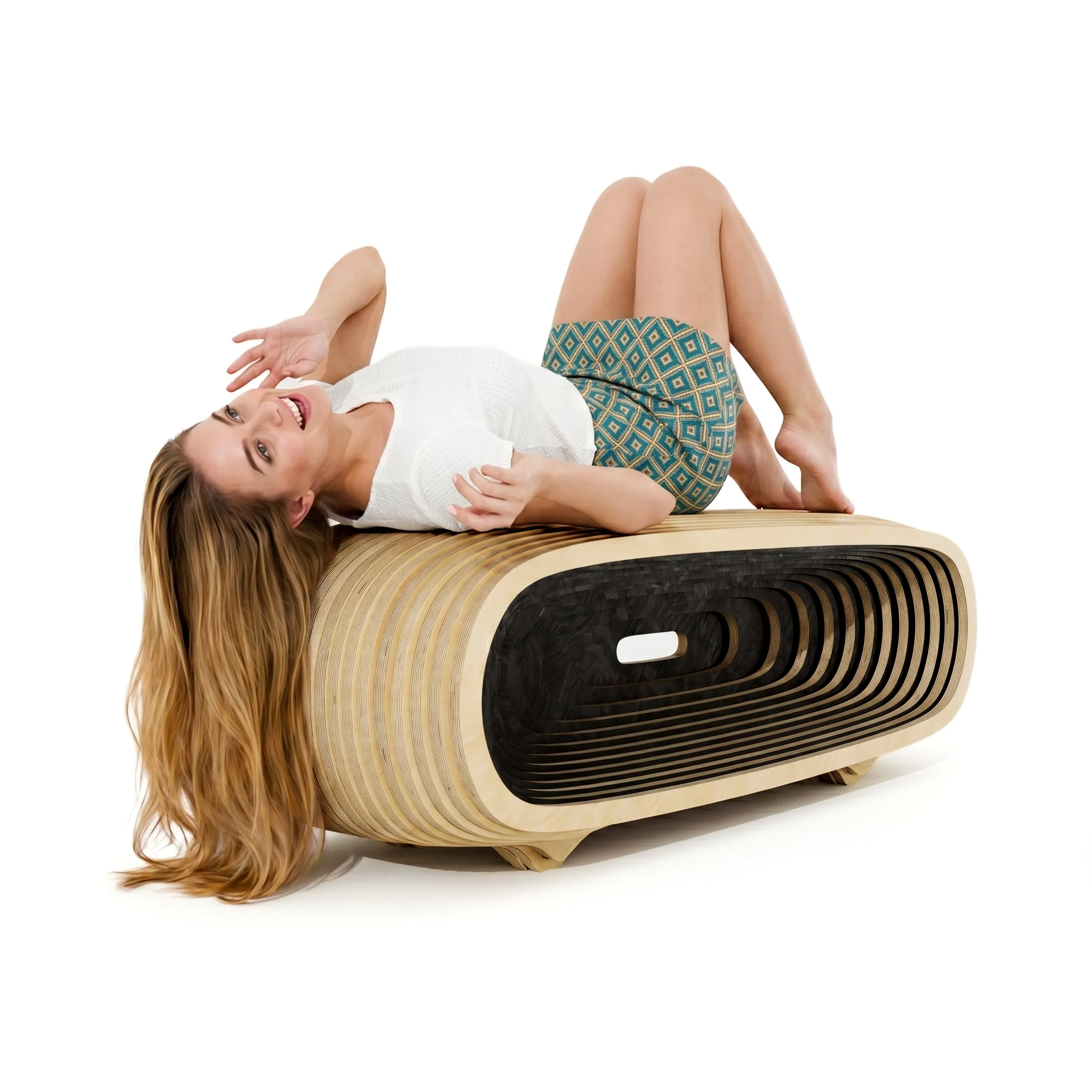 A woman with long blonde hair lying on her back on a wooden parametric bench made in a retro or modern style, smiling, wearing a white top and patterned shorts, with her arms up.