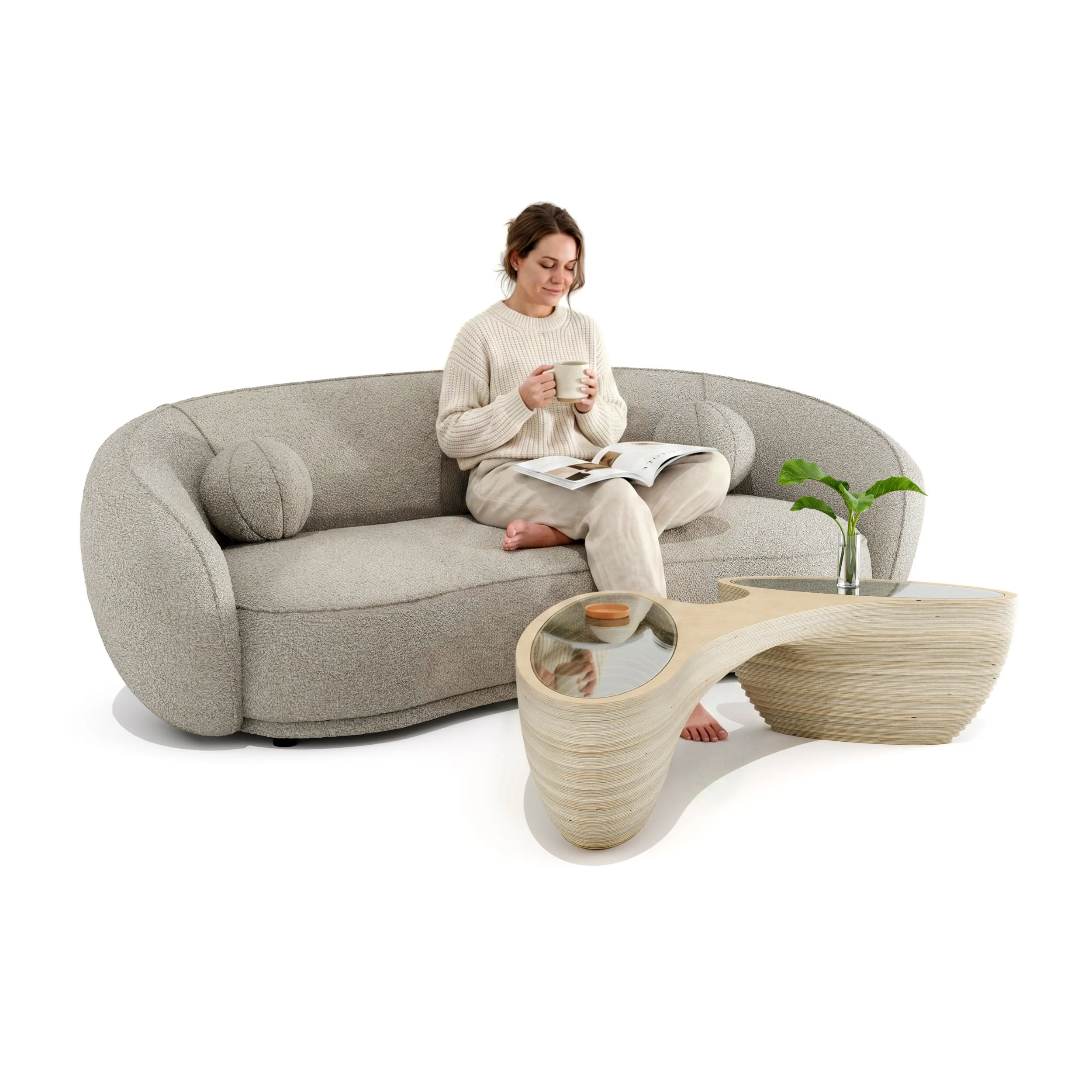 A woman sitting on a beige sofa, holding a white mug, looking at an open magazine, with a sculptural wooden coffee table in front and greenery in a glass vase nearby, against a plain white background.