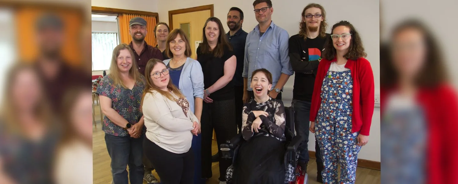 A group photograph of the Beacon Films staff team and board of directors. There are 11 people in the photograph. Most people are standing. One women is a wheelchair-user. Everyone is smiling at the camera.