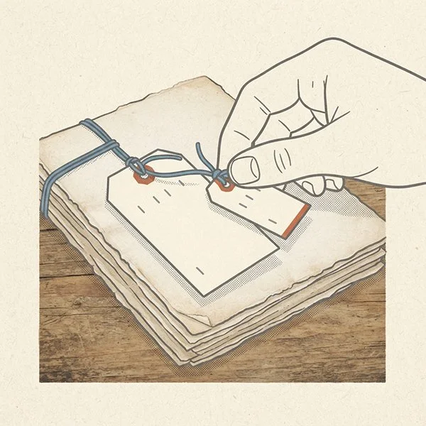 A hand swapping one small price tag for a smaller one on a string tied to a stack of manuscript pages.