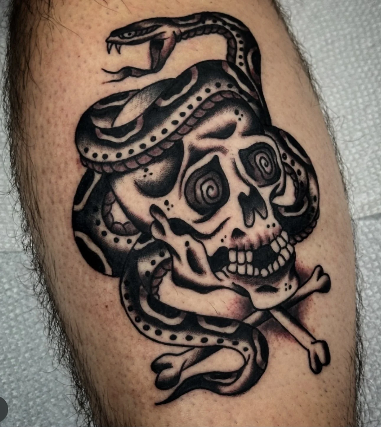 Fresh black and grey traditional skull and snake tattoo during early healing