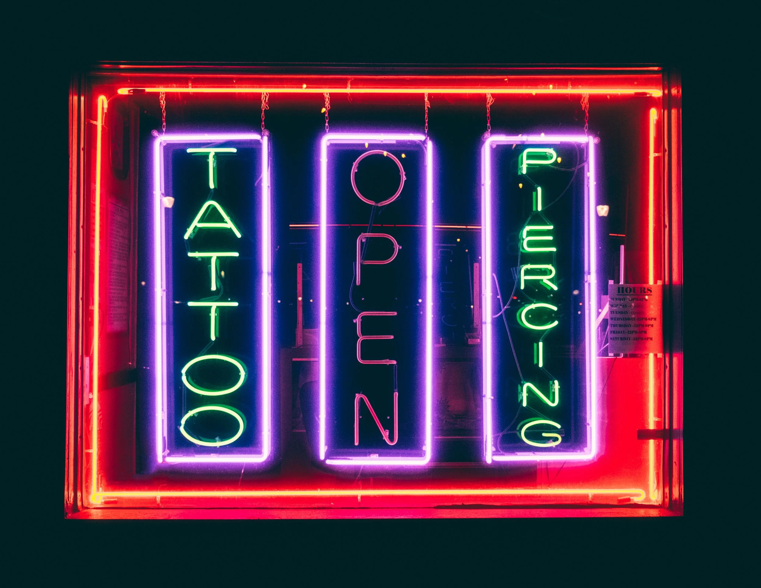tattoo and piercing shop neon sign in Atlanta studio window