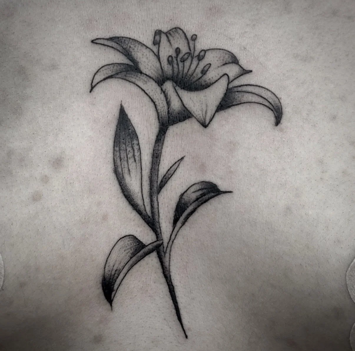 Fine line flower tattoo with delicate shading and minimalist design