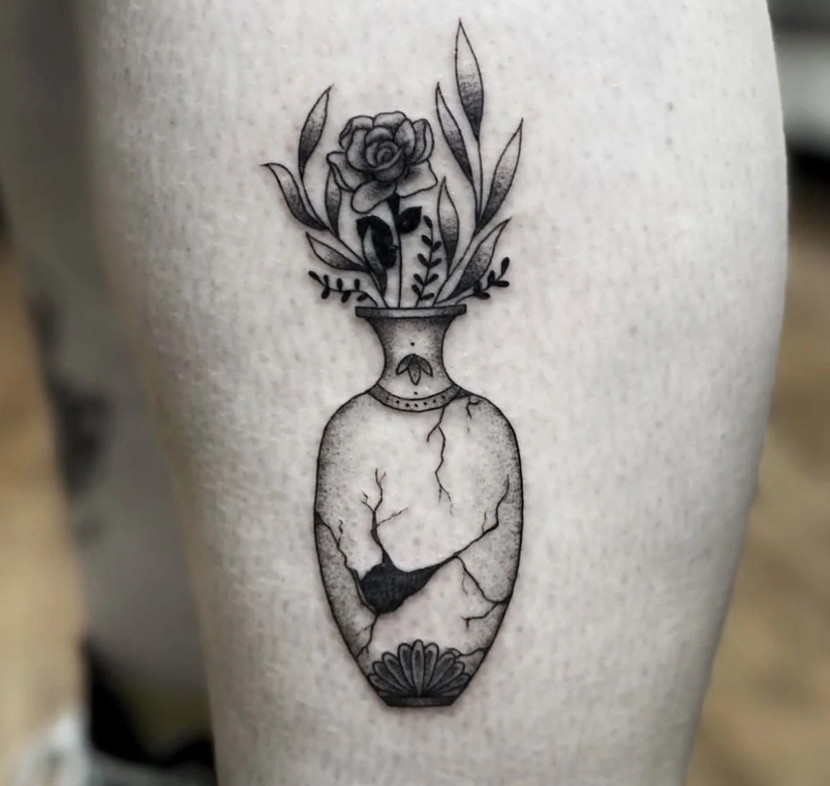 Fine line tattoo of a vase with floral arrangement and soft shading
