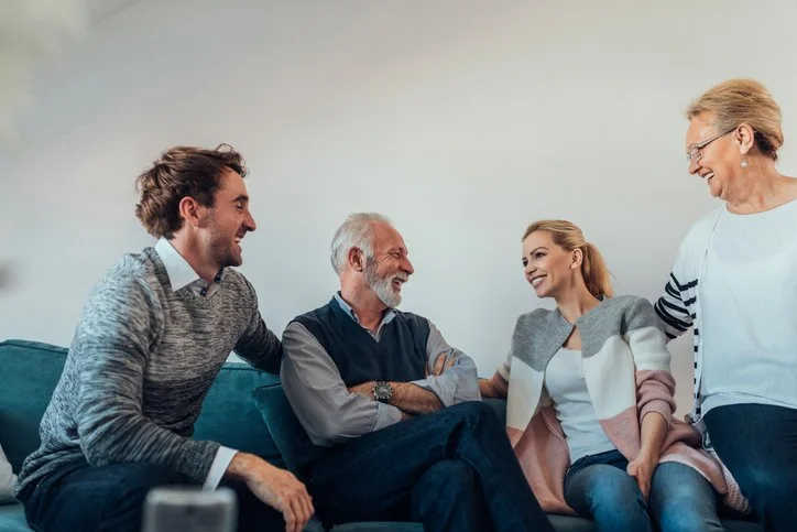 Adult children talking to their parents, smiling and laughing on couch