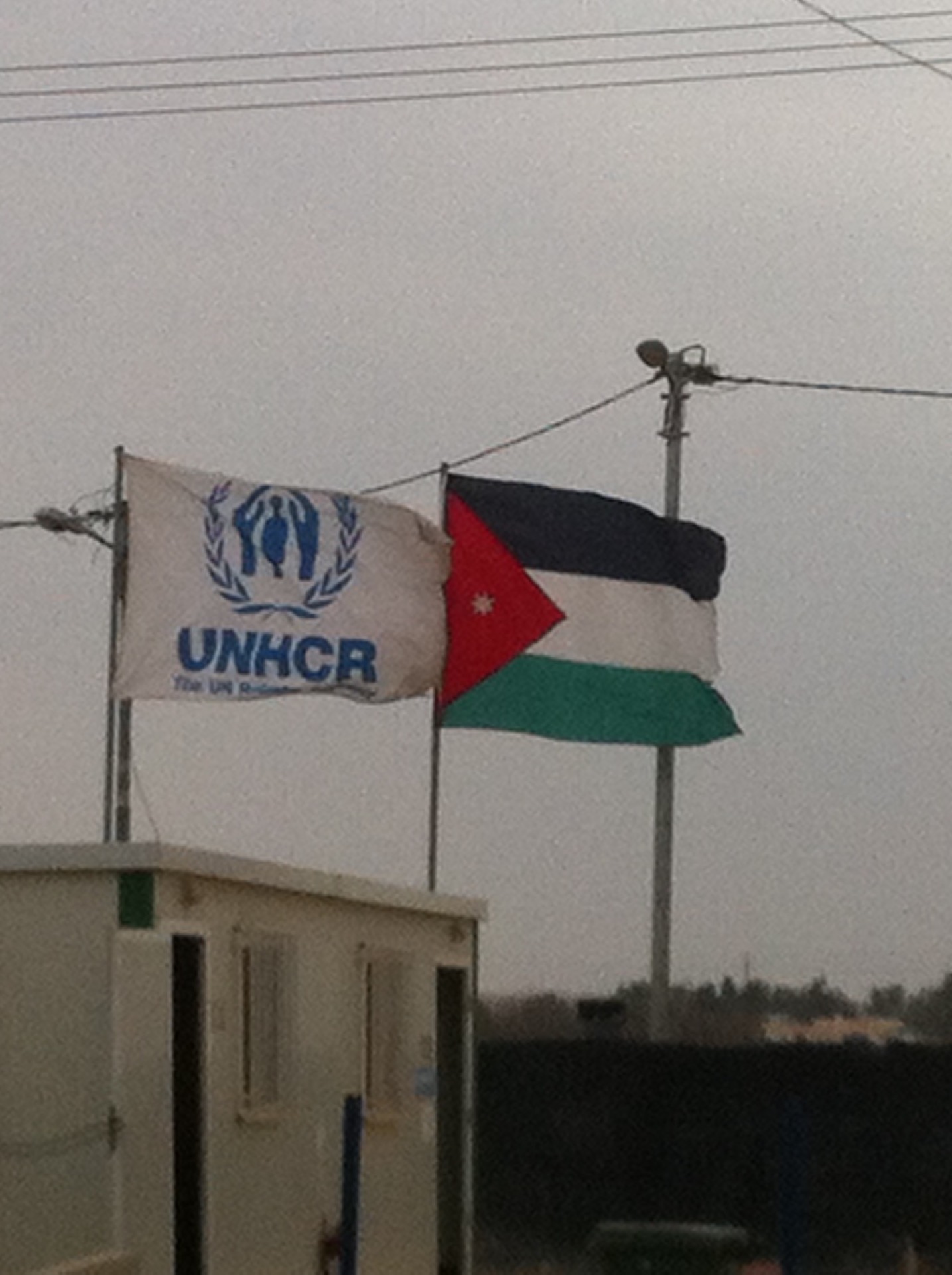 UNHCR and Jordanian flags stand at the entrance to Base Camp, the centre of humanitarian operations in Za’tari, 3 March 2016. Photo by Lewis Turner