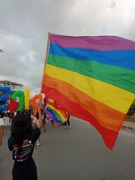 A person holding up a rainbow pride flag at a pride march in Timor-Leste.