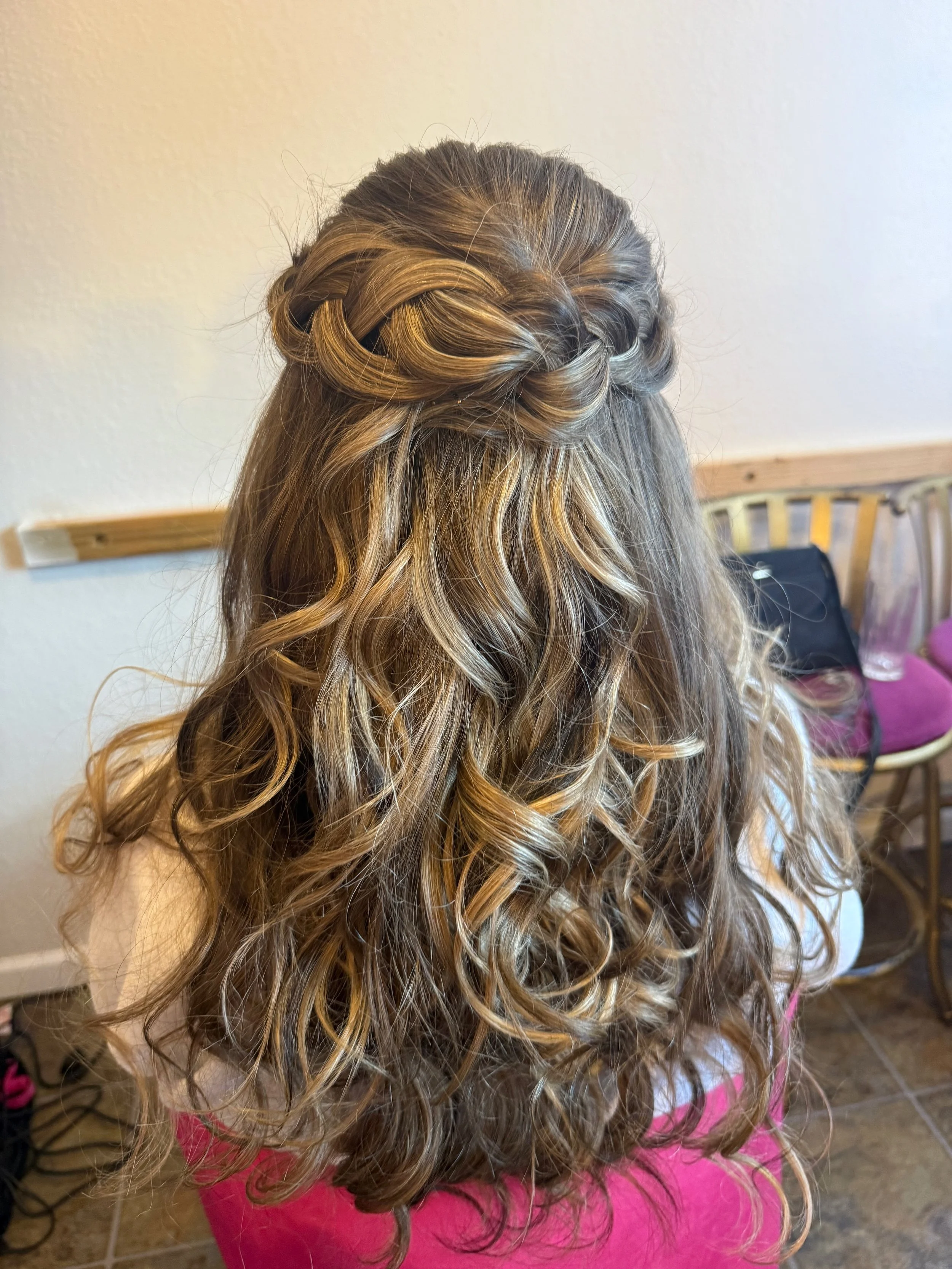 Back view of a bride with long, curly, blonde hair styled with braids and twists.