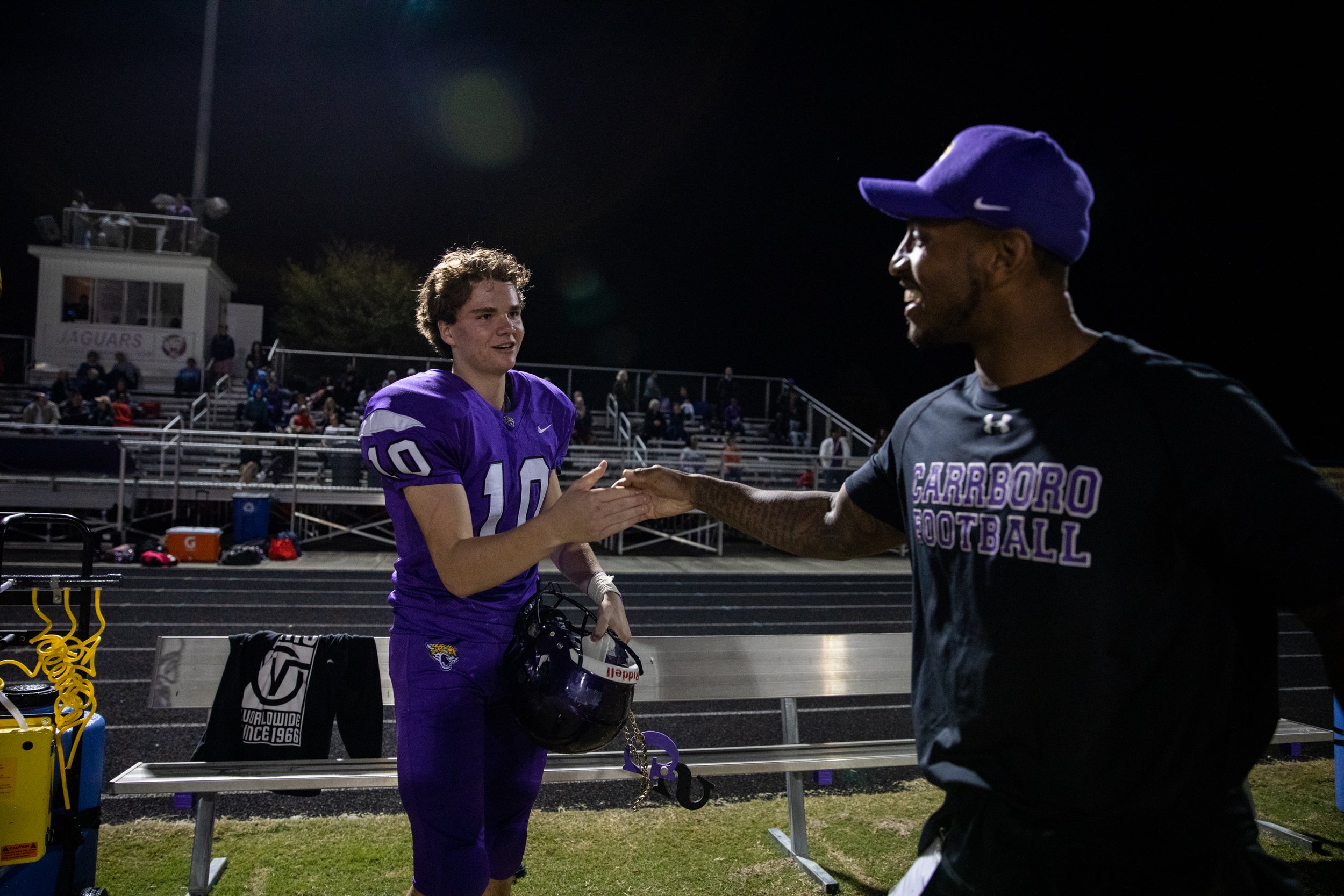  Special Teams Coach Fred Dale congratulates Jake Adams, a junior on the Carrboro High School football team, and gives him a special GS Necklace, short for “Goon Squad,” that Dale made to give to his players whenever they complete a special teams pla