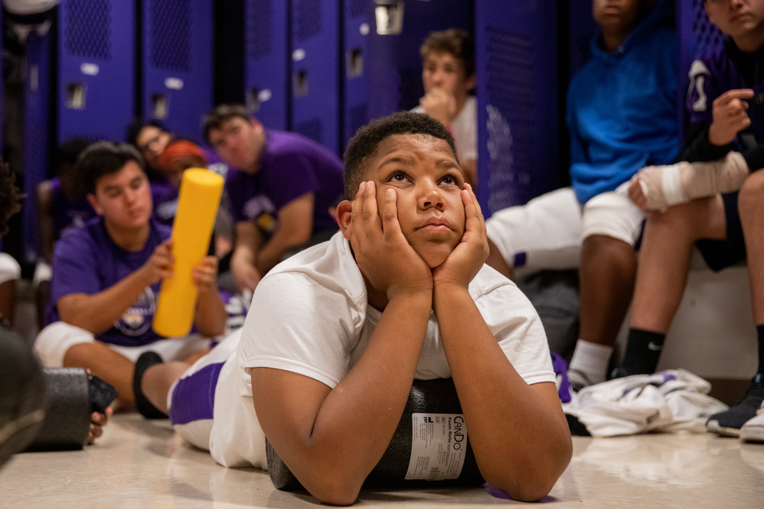  The 33 players and seven coaches that comprise the team all squeeze into one men's locker room in order to discuss the plays they want to perform during the games. Jevontay Paisant, a freshman on the team, listens to the coaches as they prepare for 