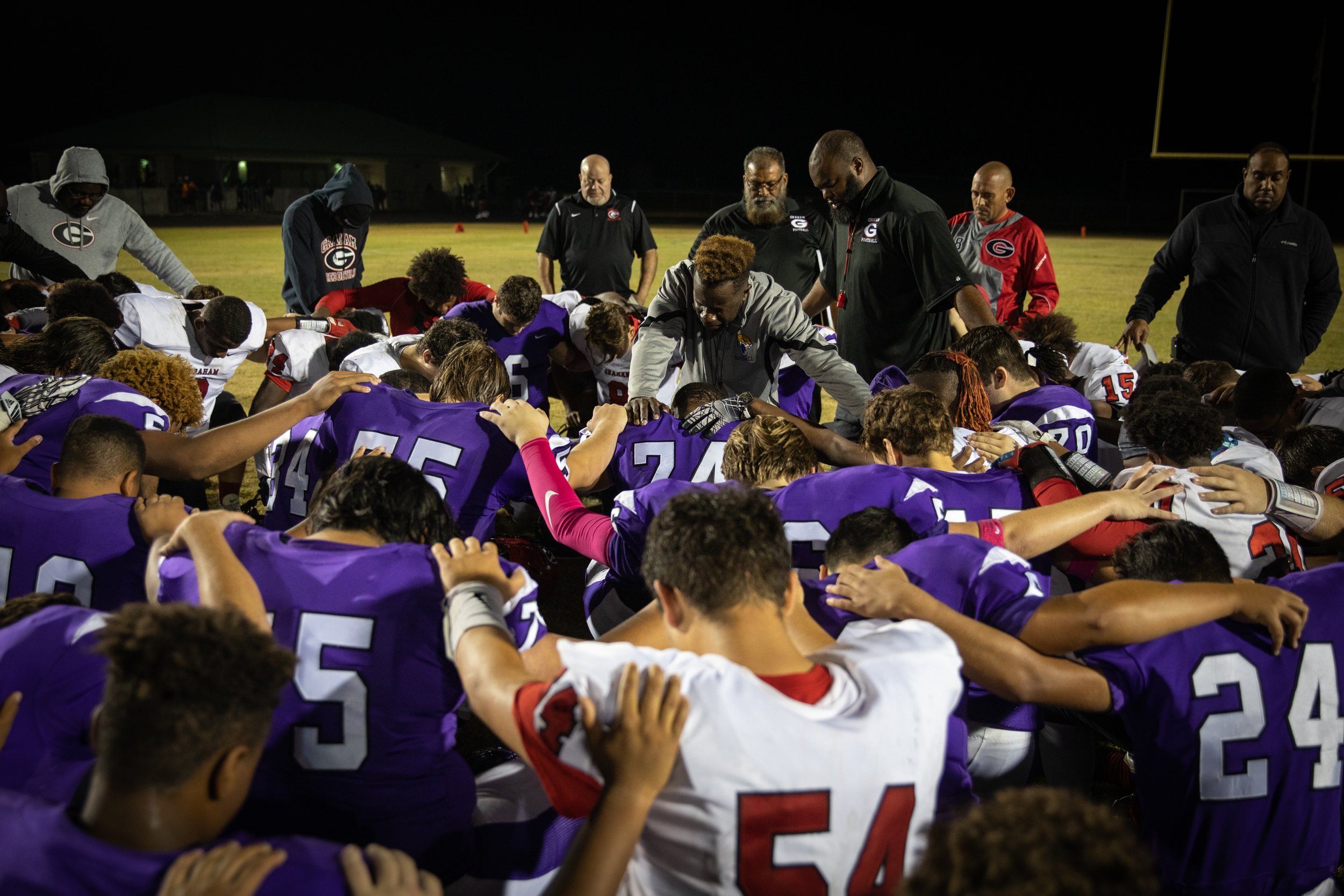  Coach Lathan leads a prayer with players from both football teams after Carrboro beat Graham High School, 22-0. “I have built this program on three simple principles... God before all, team before me, and be the best that I can be,” Lathan said.  “I