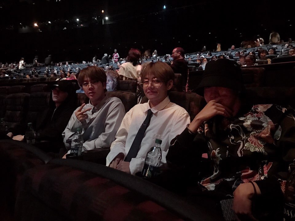  j-hope, V, Jin, and Suga sitting in the theater for the KA Cirque Du Soleil show 