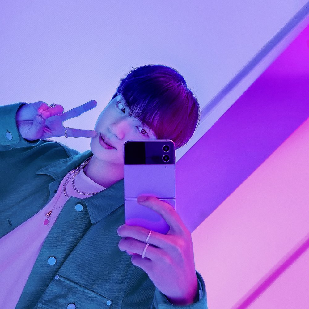 Jin in green &amp; purple taking a selfie with the Galaxy ZFlip4. 