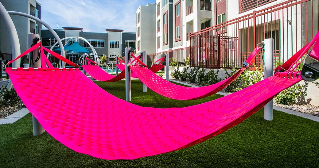 Several Ting Sling seatbelt hammocks, as seen in the pool area of a luxury apartment complex.