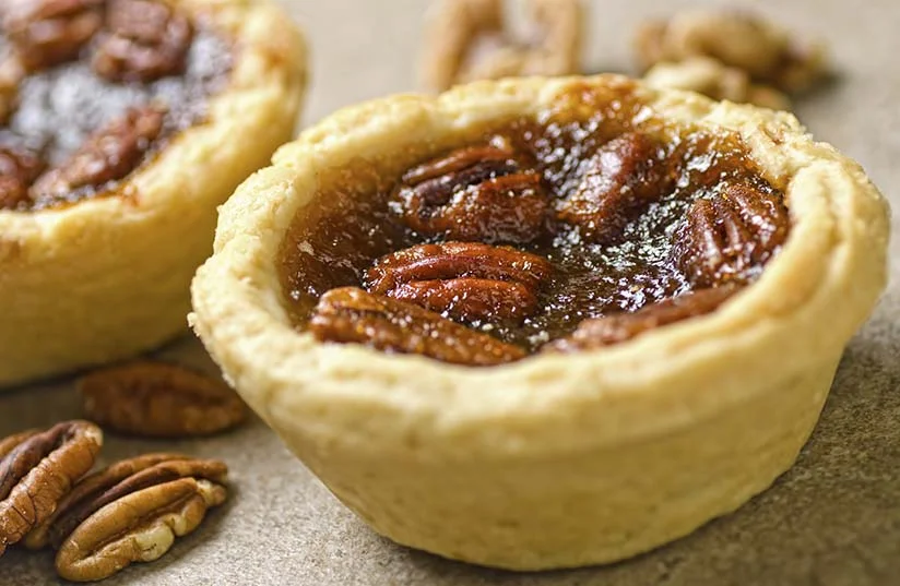 Closeup-photograph-of-pecan-tartlets-and-pecan-nuts-000021956816_Large.jpg
