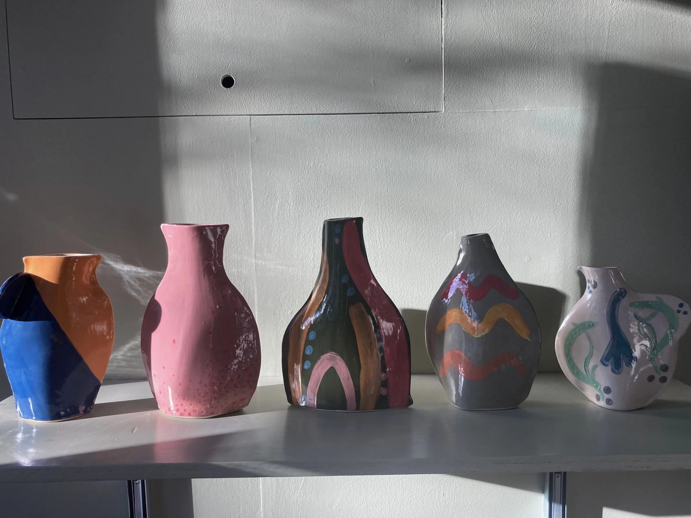 Handmade terracotta bottle vases with handles on display