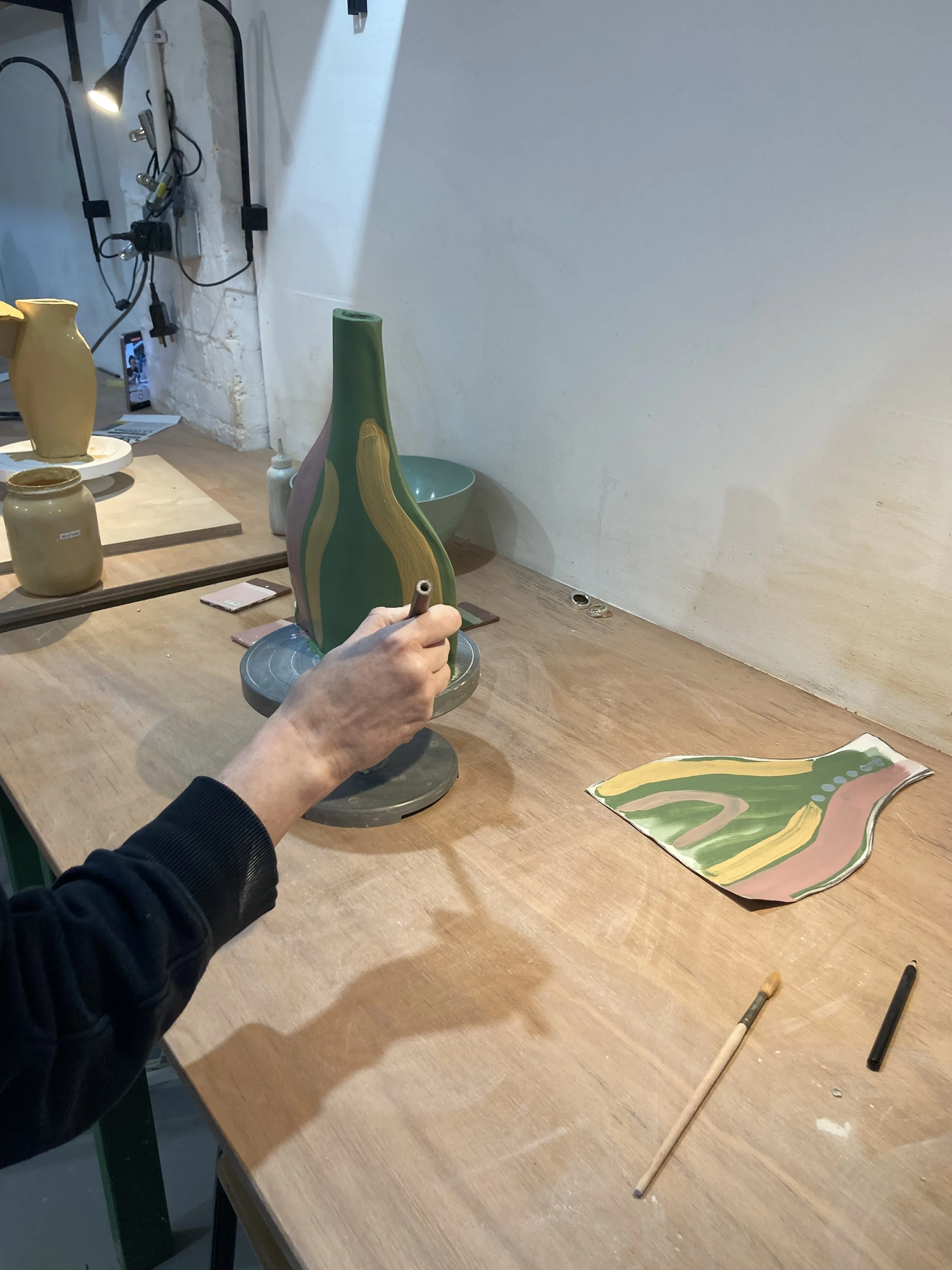 Decorating terracotta vase with coloured slip in ceramics workshop