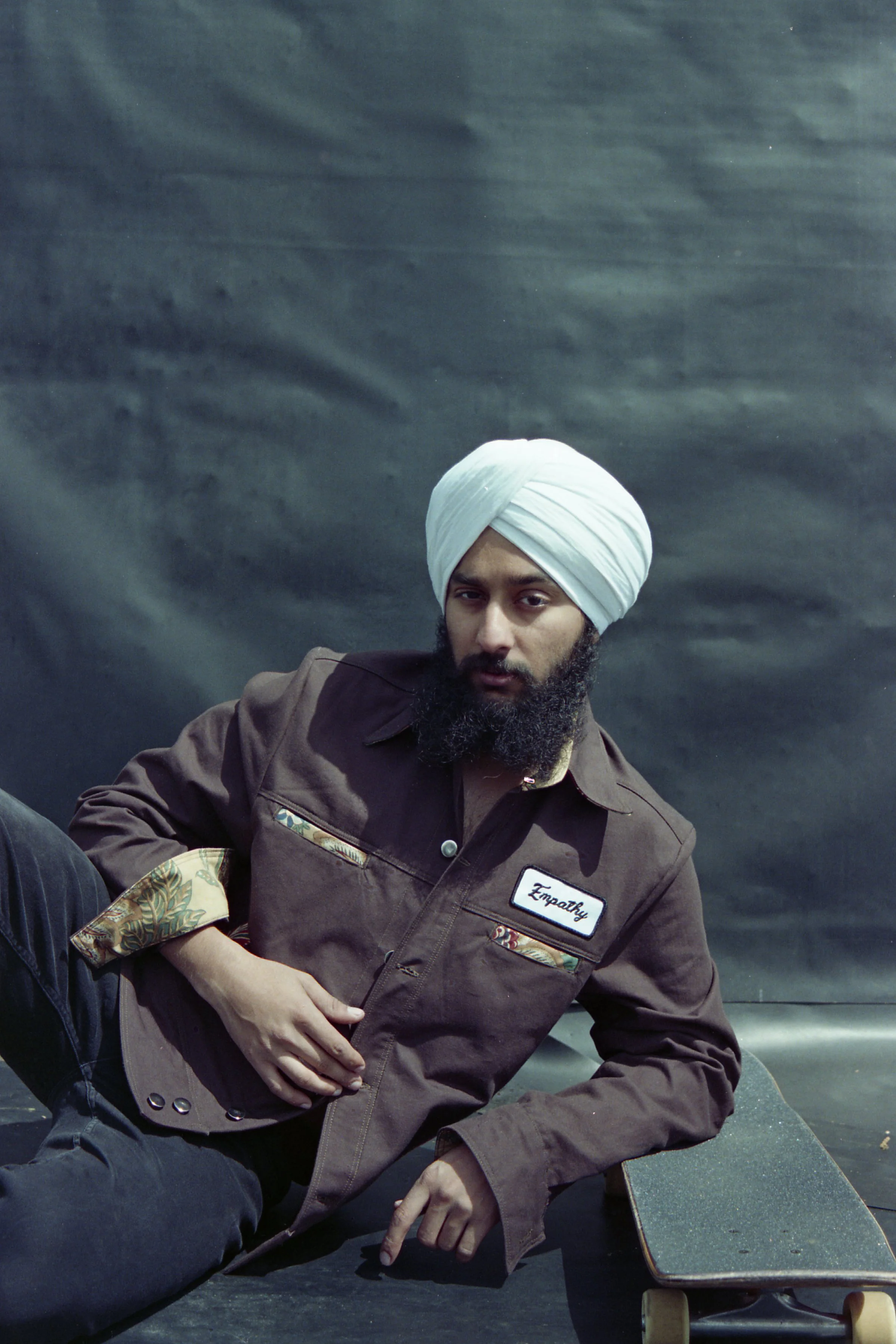 Model resting on his board wearing the 'Empathy' Cotton Canvas original jacket by Slow Process