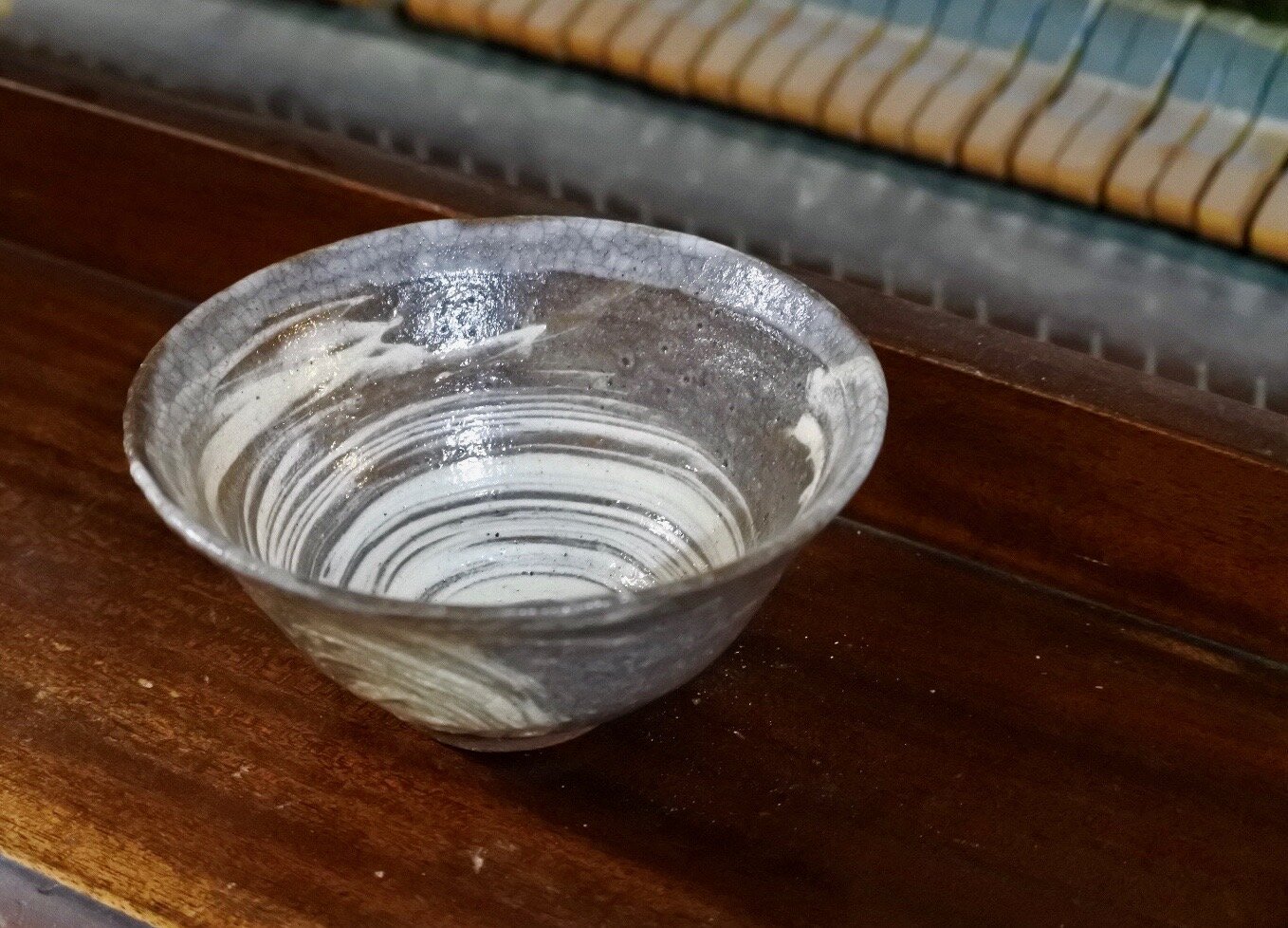 Korean style tea bowl sitting on top of an old piano.