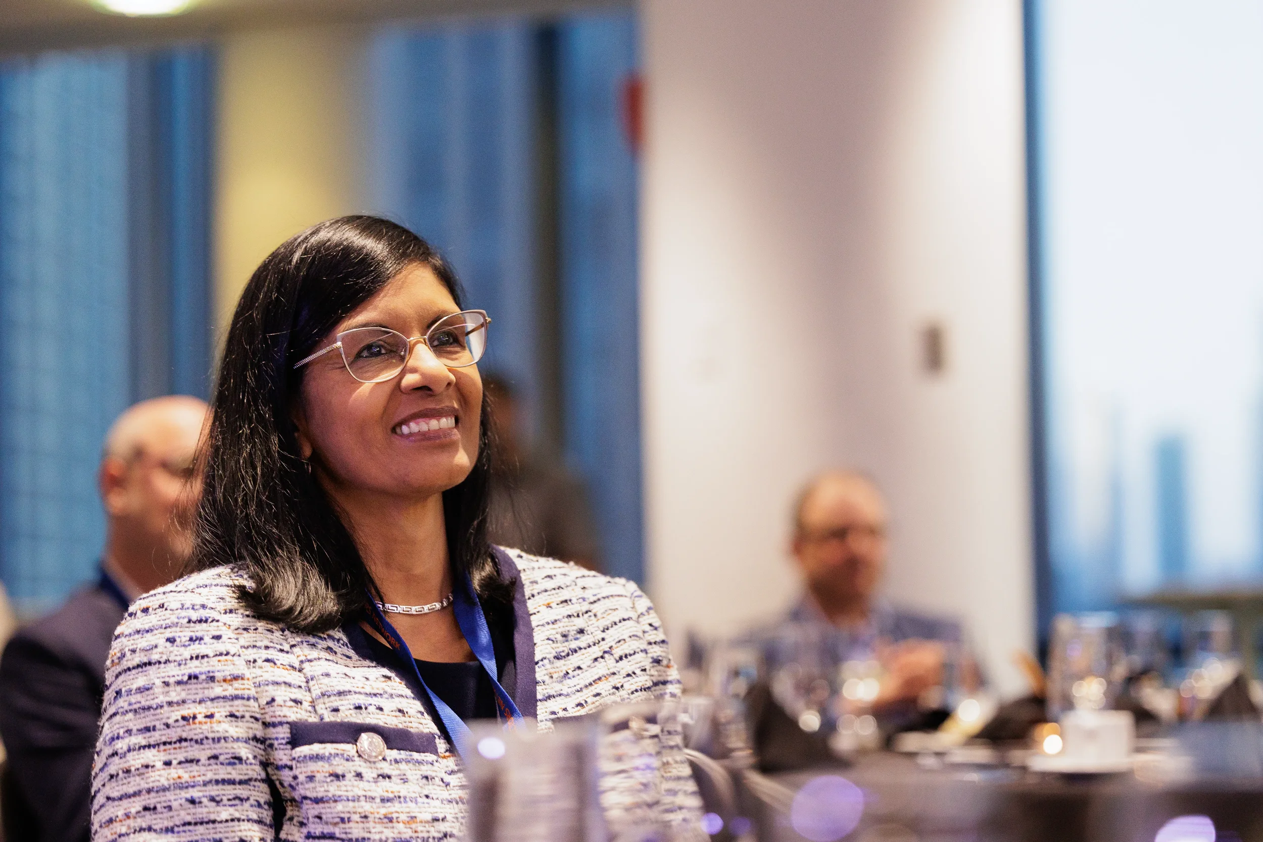 Smiling female attendee with lanyard seated at table during Chicago corporate conference session
