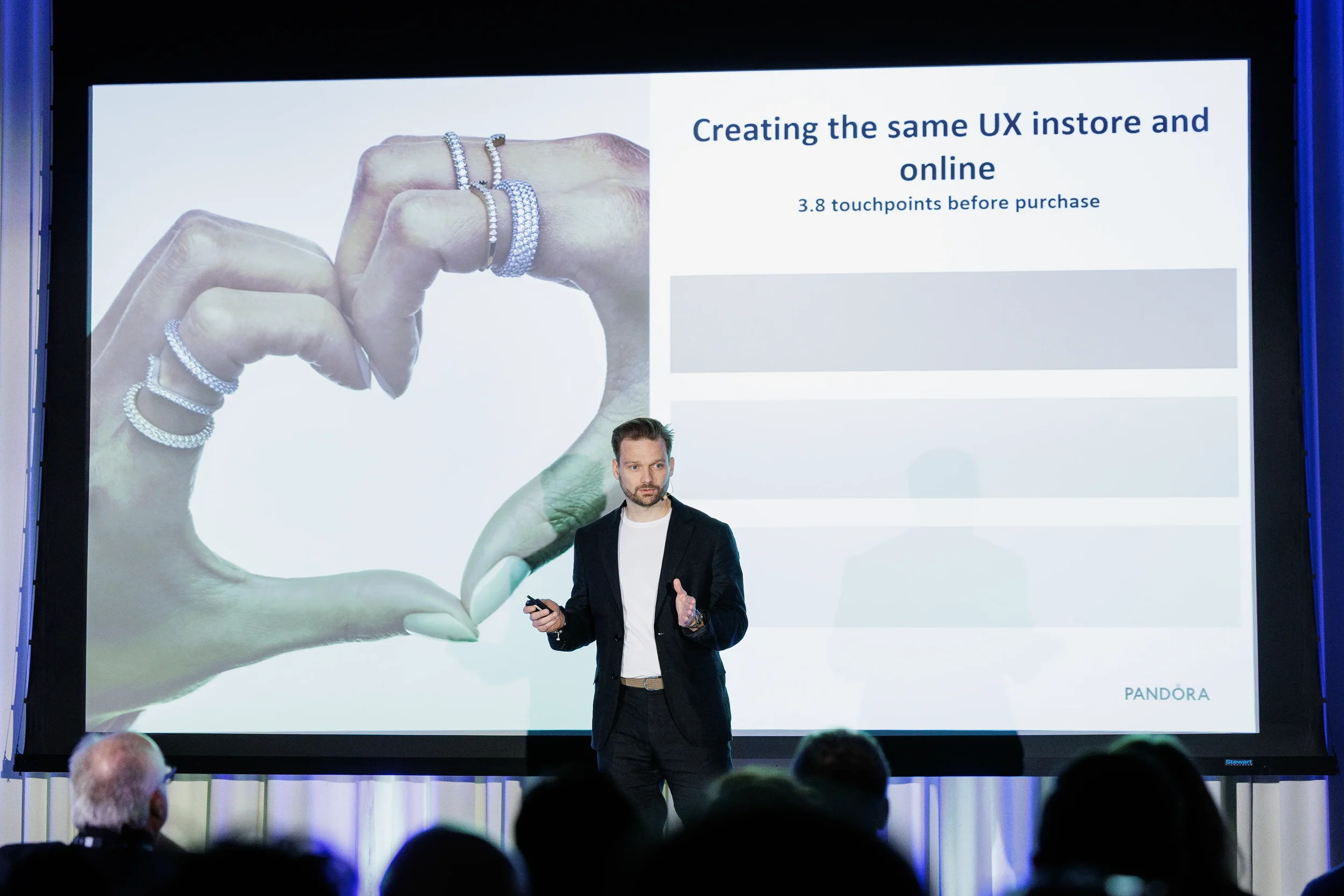Speaker presents beside jewelry slide on stage before audience at Orlando industry conference