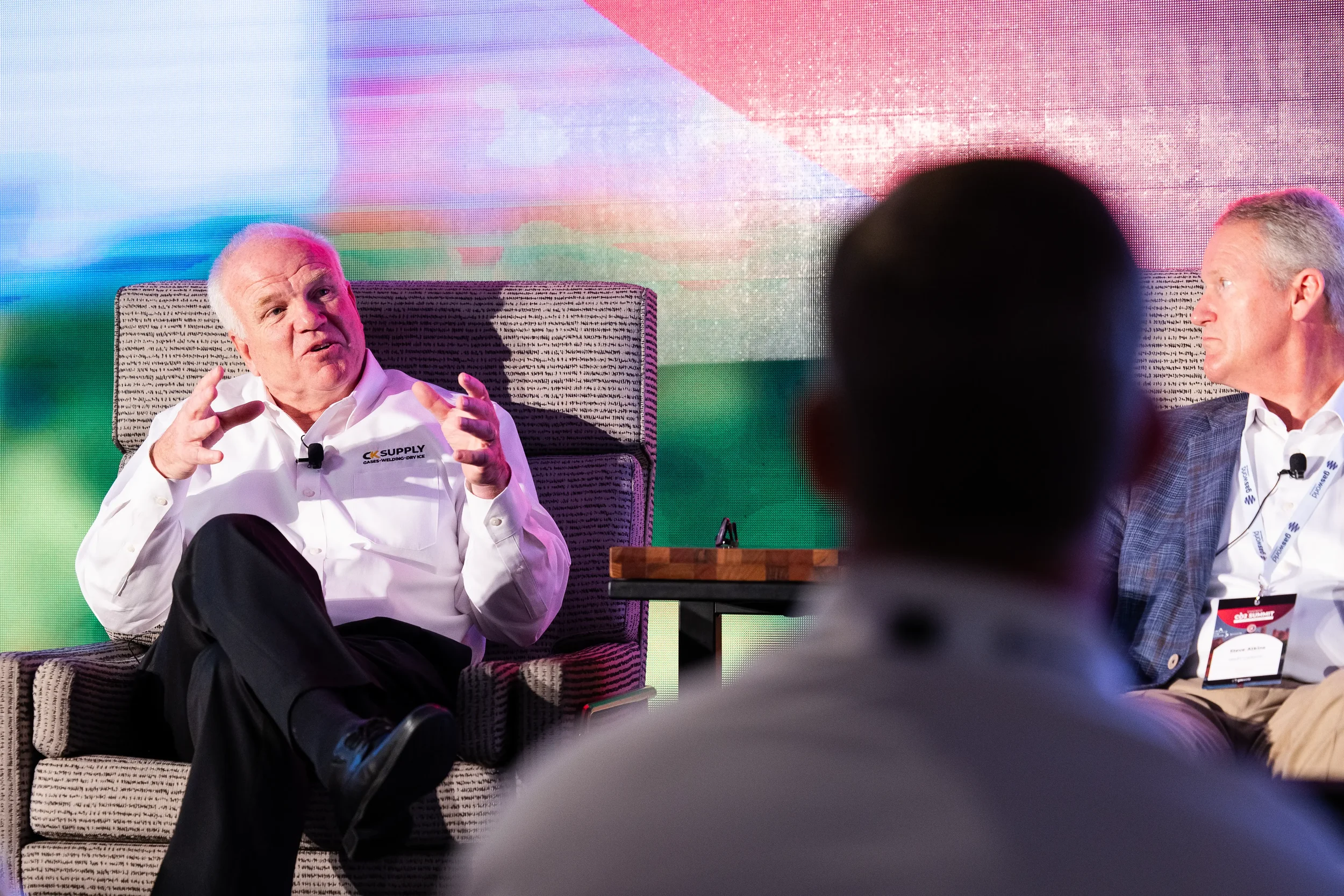 Two panelists engage in fireside chat on stage with audience silhouette in foreground at Chicago summit