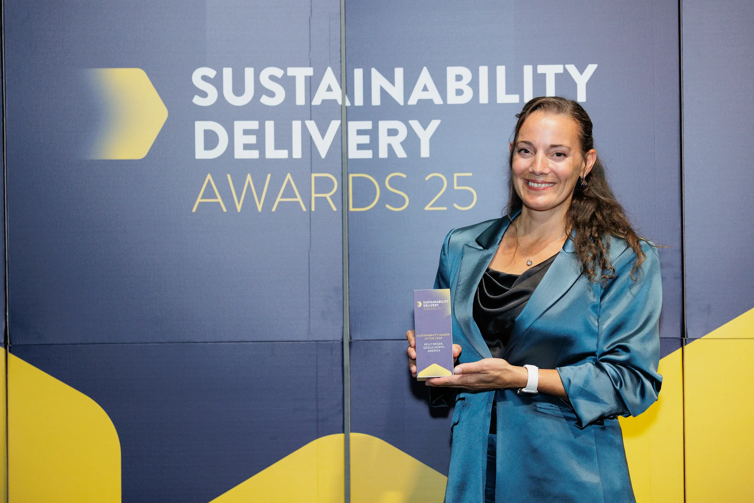 Award winner poses with trophy in front of branded backdrop at Chicago corporate awards ceremony