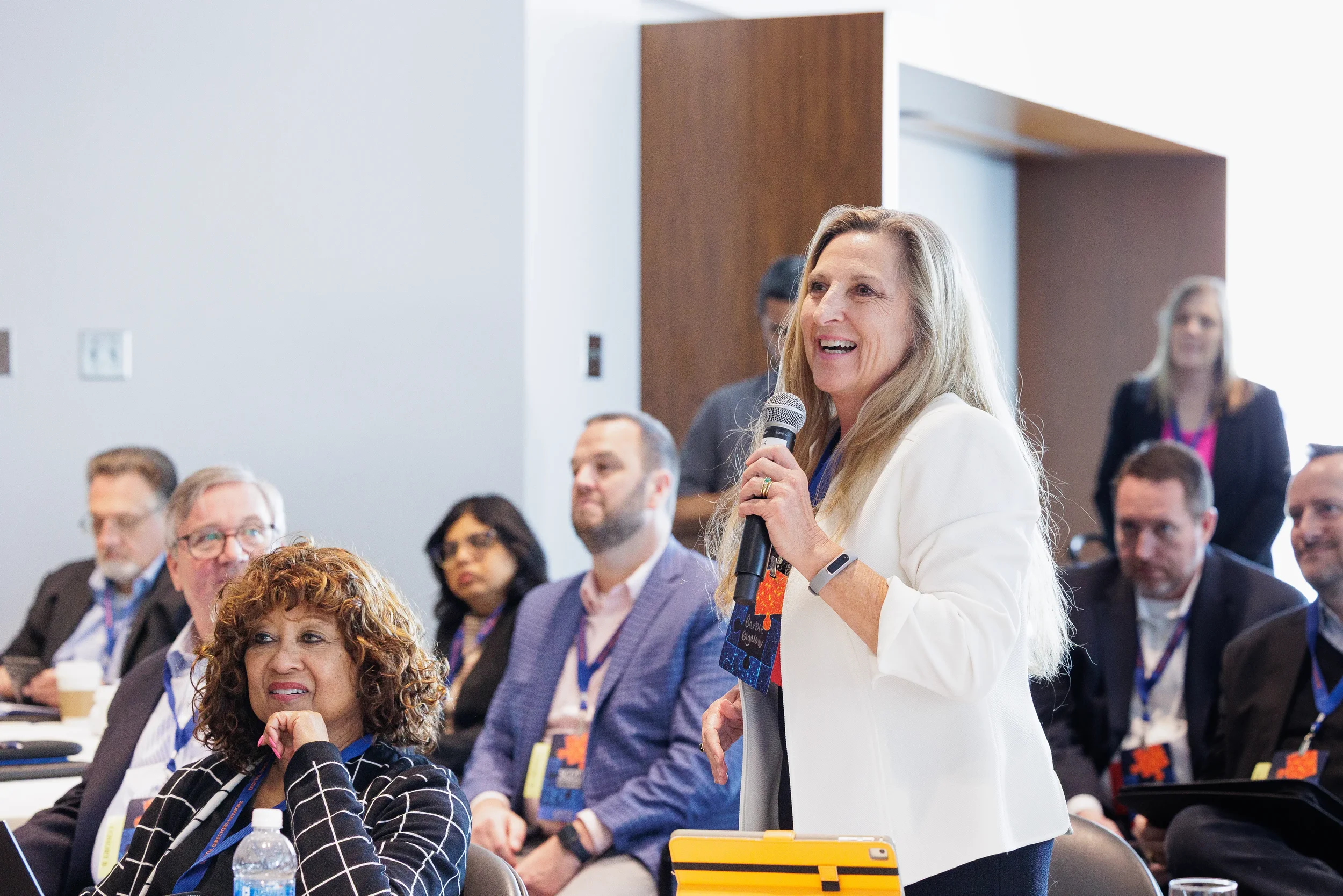 Female attendee stands with microphone to ask question during Orlando corporate conference session