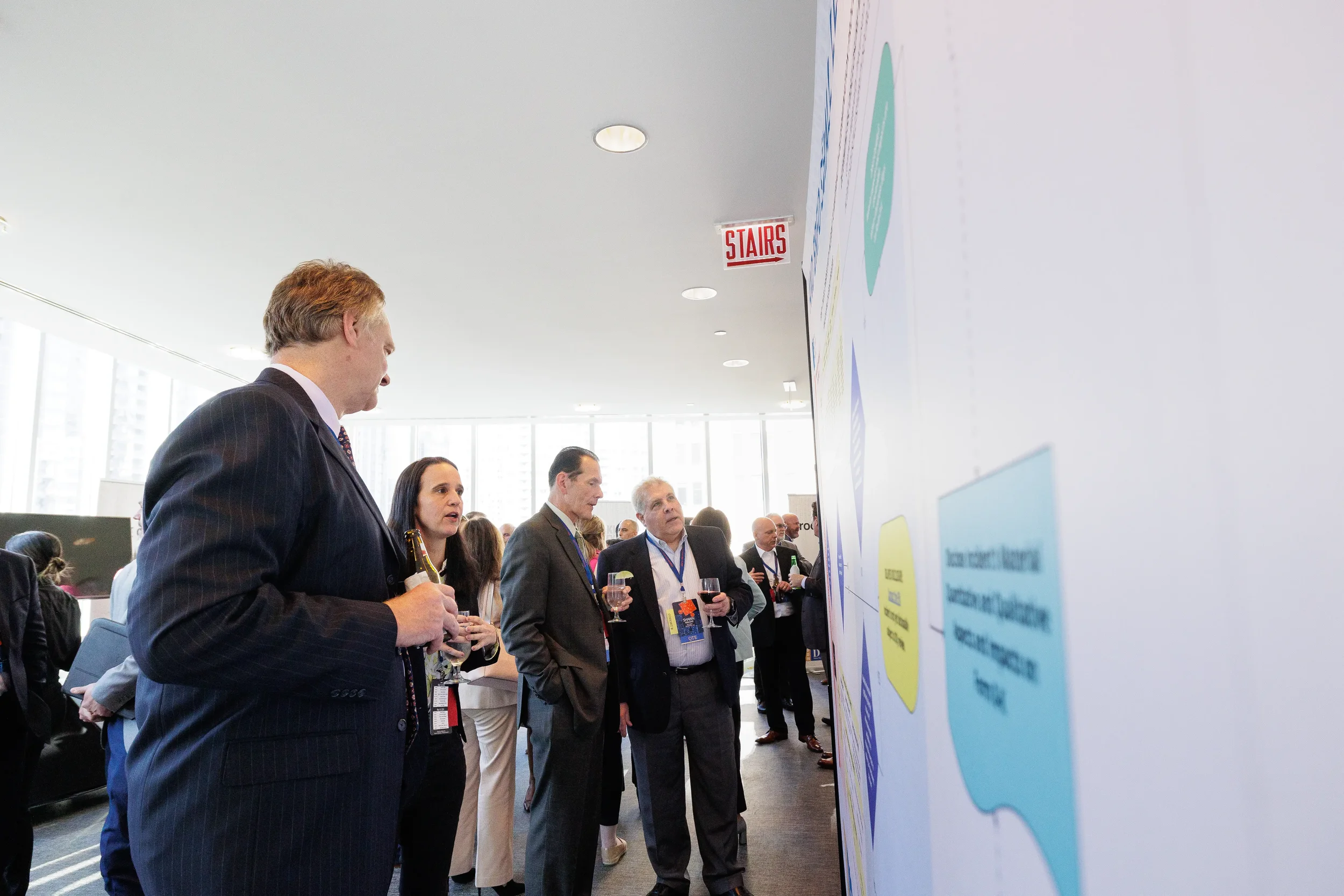 Attendees with drinks review large diagram display board during Chicago corporate conference networking