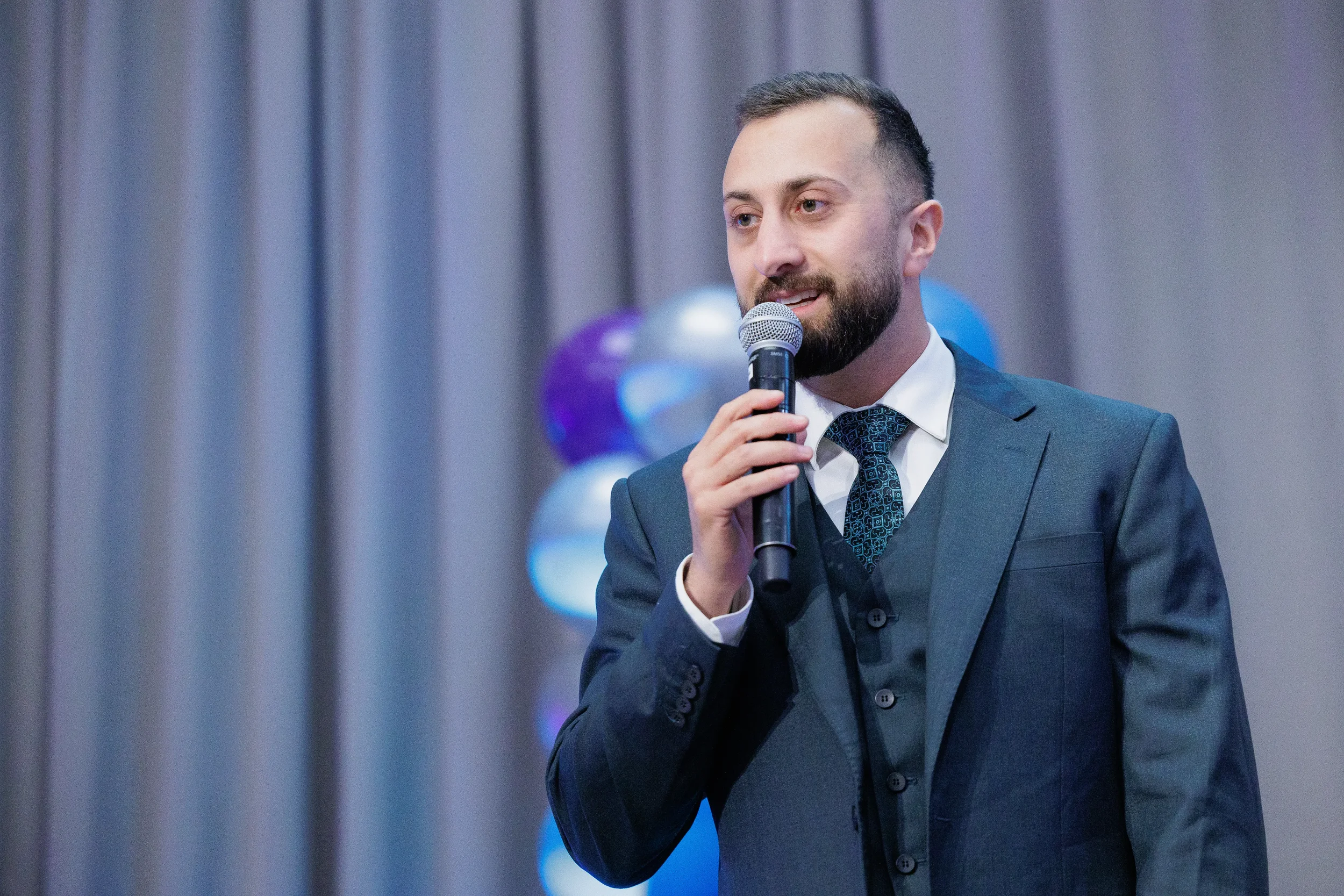 Suited speaker addresses audience with handheld microphone at Chicago corporate event