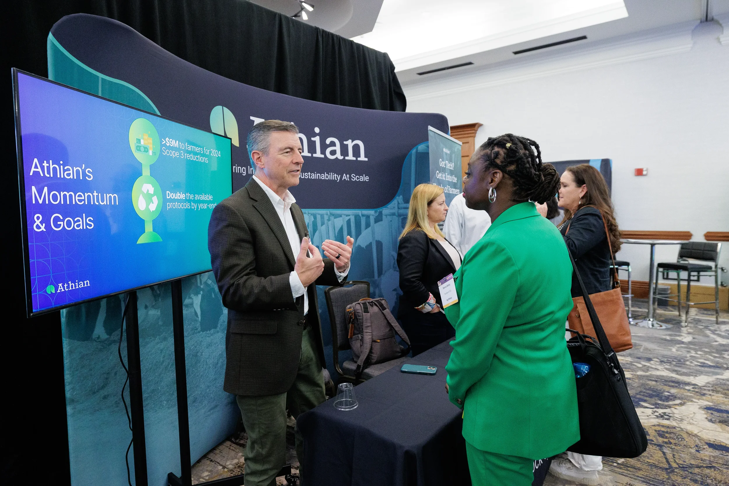 Attendees converse near presentation screen at expo booth during Orlando corporate conference